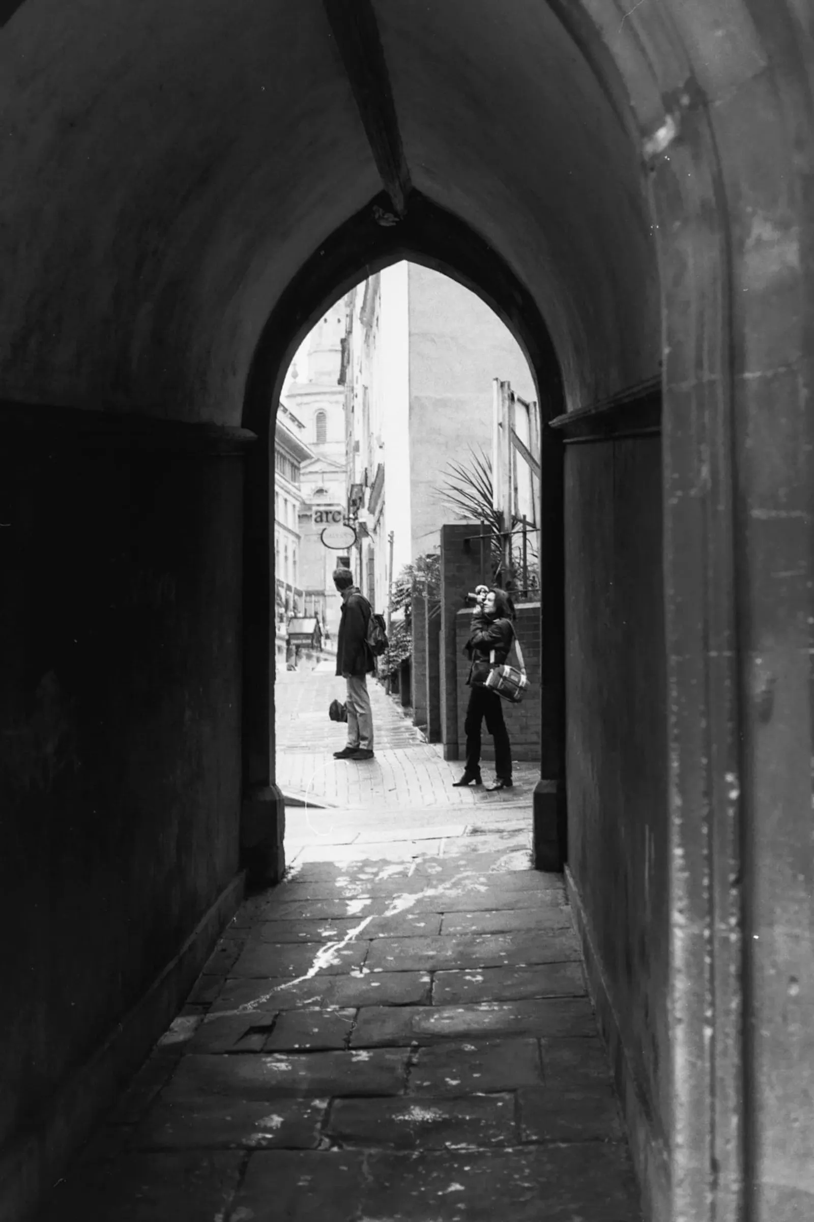 Seen through a stone arch, a woman is taking photos