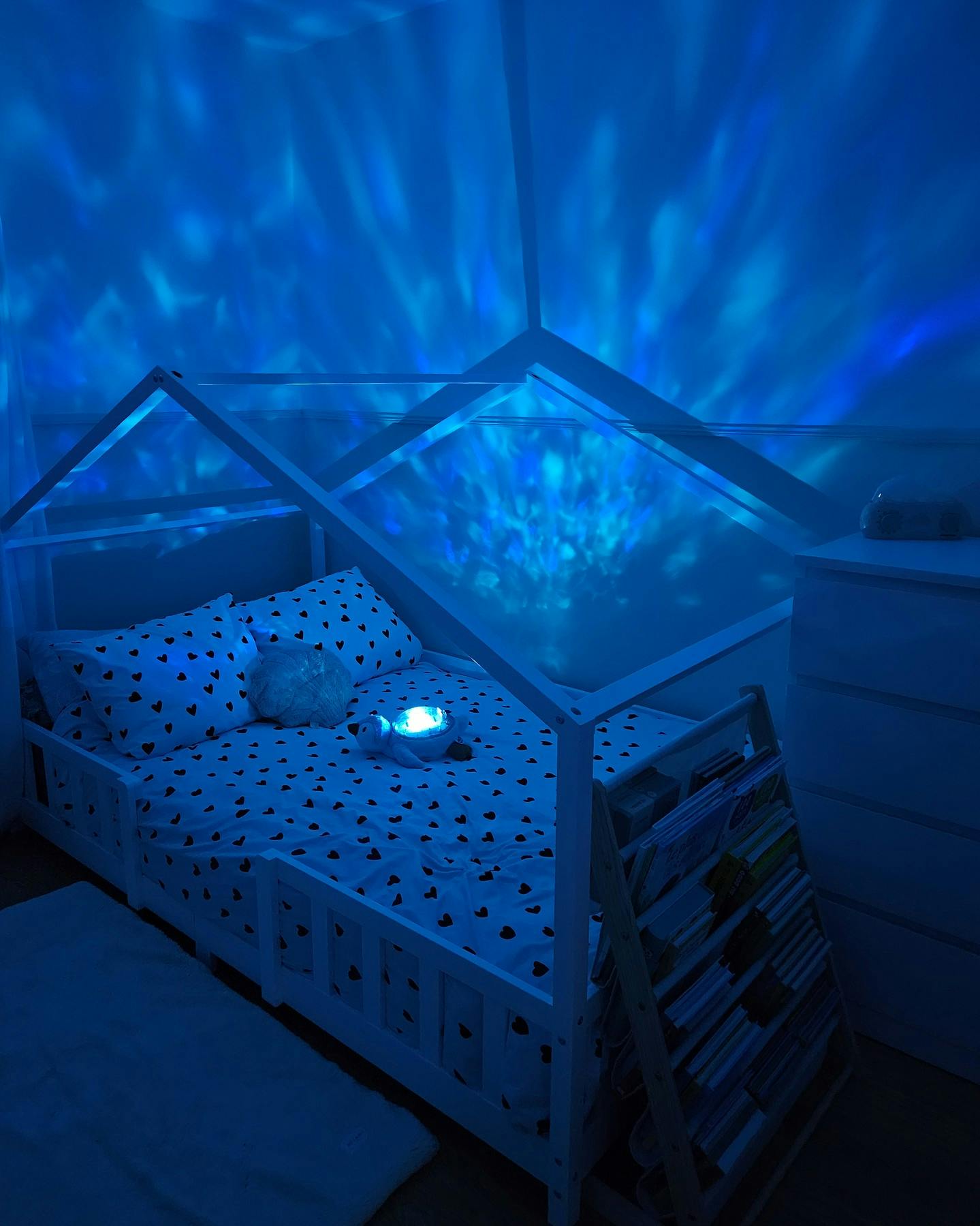 Eine Stofftier-Schildkröte liegt auf einem Bett, an den Wänden des Zimmer sieht man strahlende blaue Schattierungen.