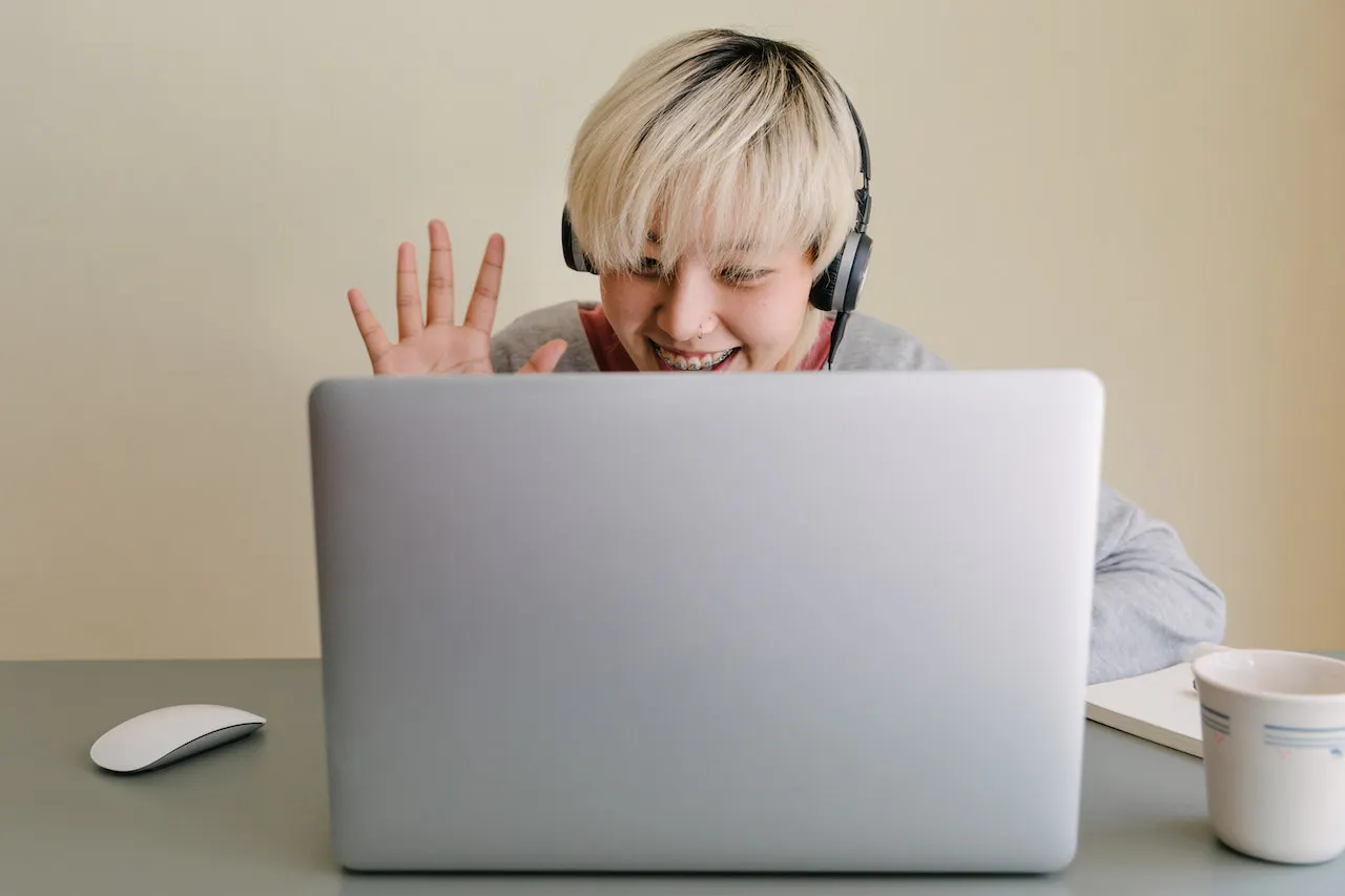 Asiatische Frau mit blonden Haaren vor einem Laptop.