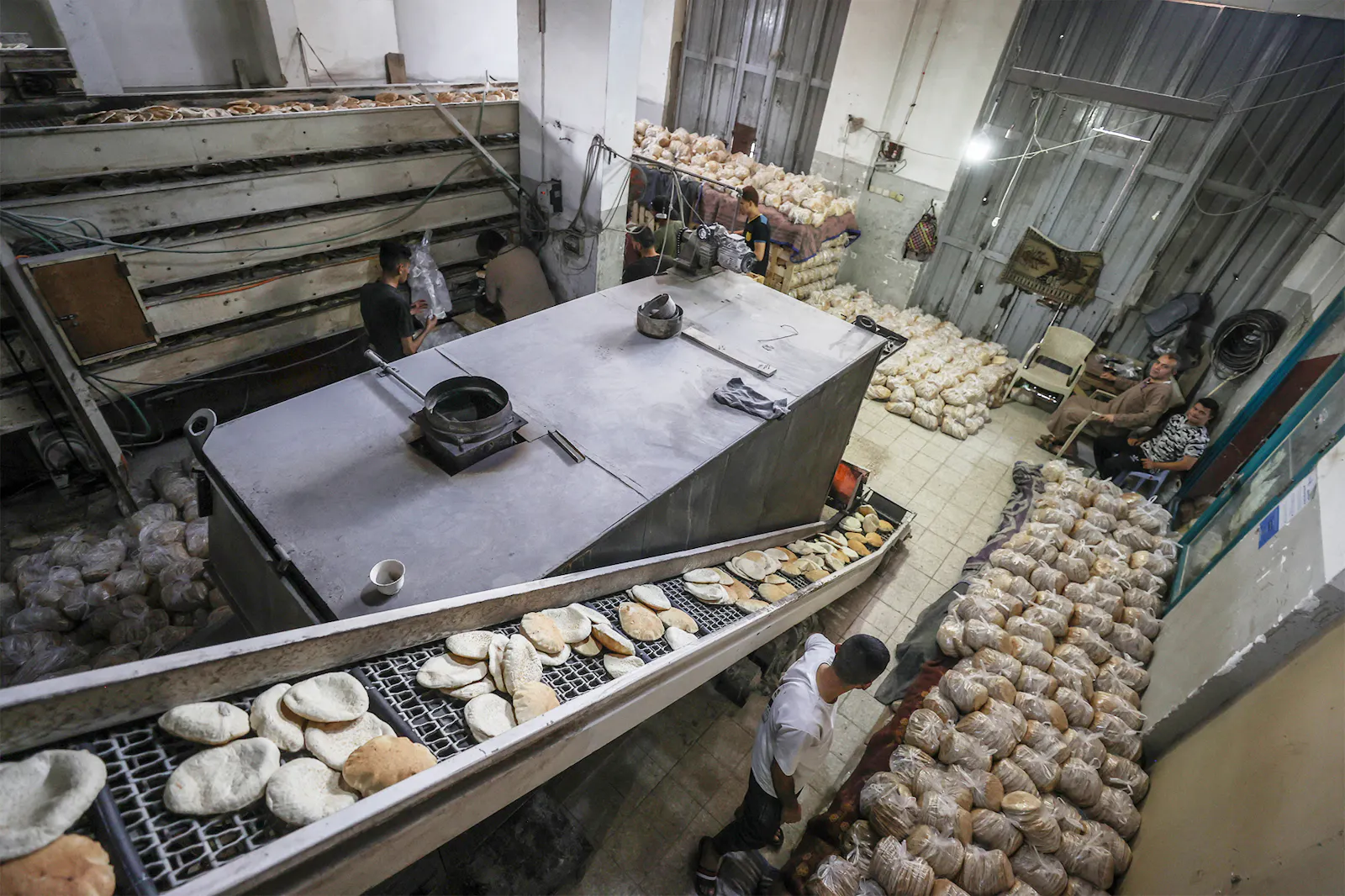 Eine Großbäckerei mit Backmaschinen, einem Laufband und tausenden von verpackten Fladenbroten.