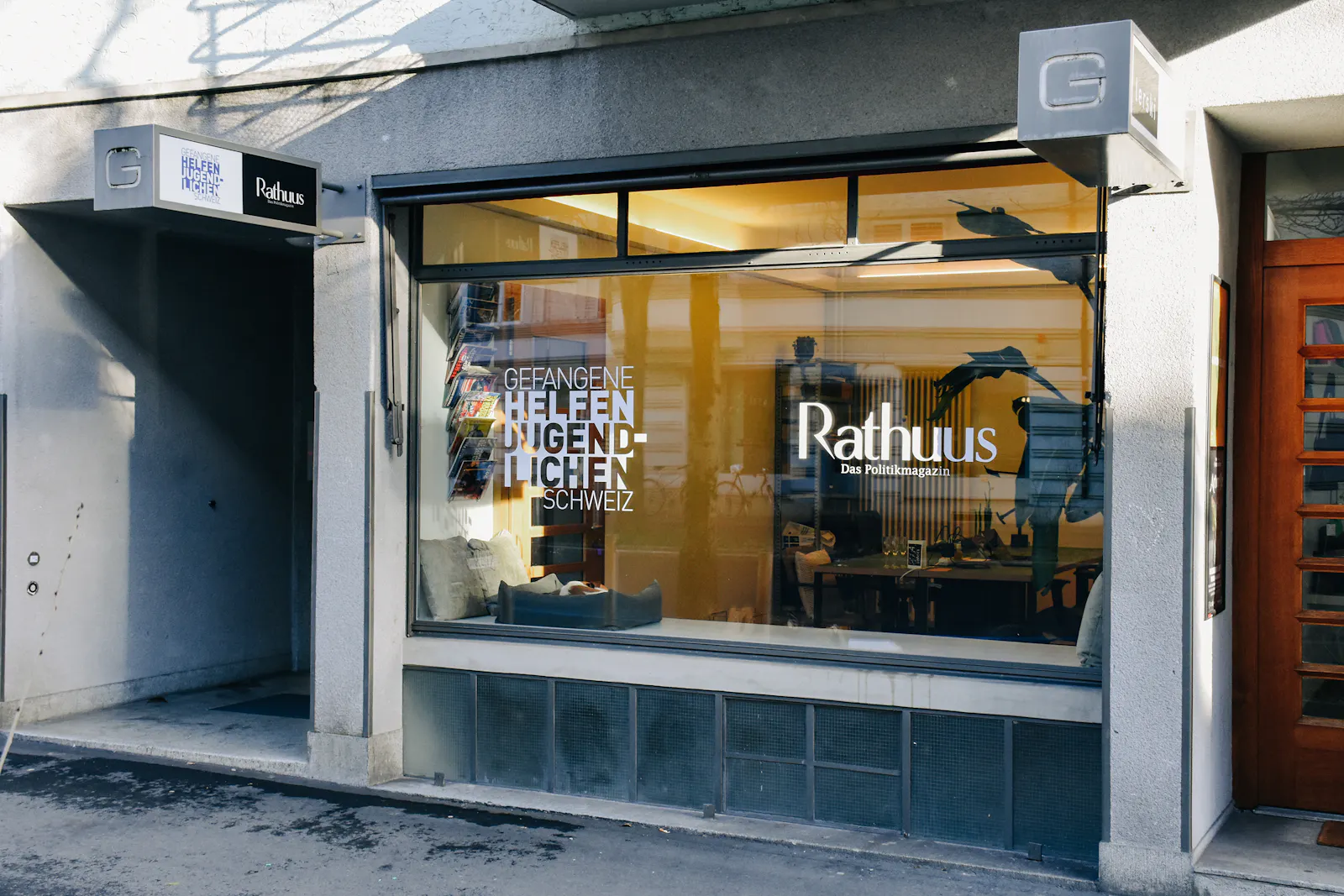 Auf dem Bild ist ein Ladenlokal mit Schaufenster zu sehen. Ein kleiner Hund liegt im Schaufenster.
