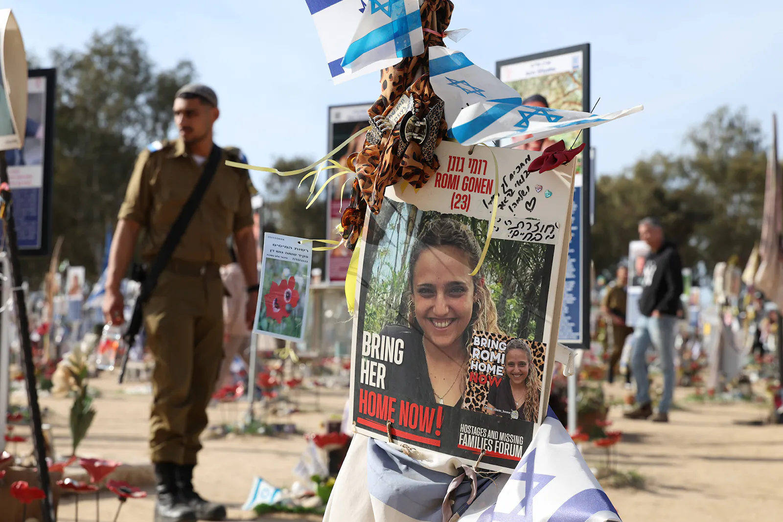 Ein Soldat geht durch die aufgestellten Pfosten, Blumen und Plakate.