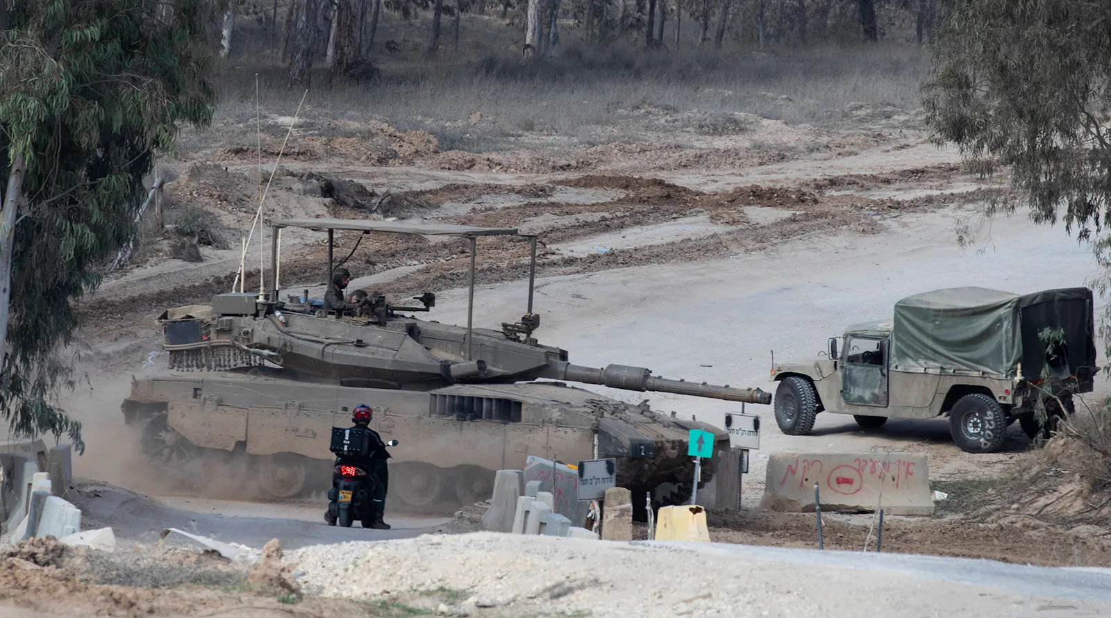 Ein Liferantenmofa steht wartend vor einem Merkava Kampfpanzer.