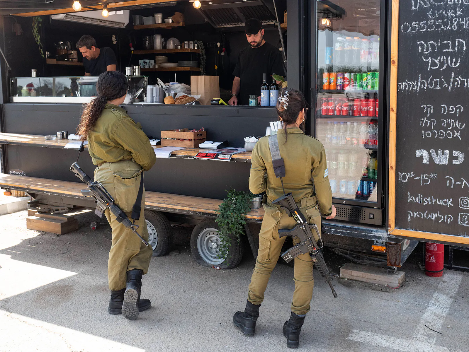 Zwei Soldatinnen mit Sturmgeweher stehen an einem Food Truck an.