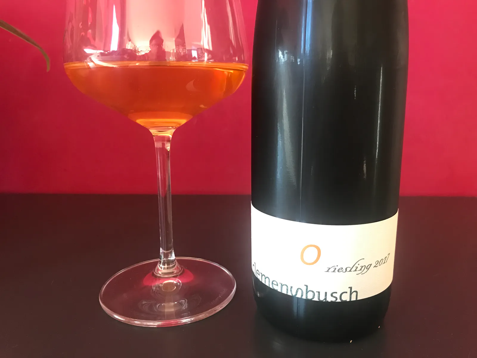 Ein Glas Wein und eine Weinflasche stehen auf einem Tisch.