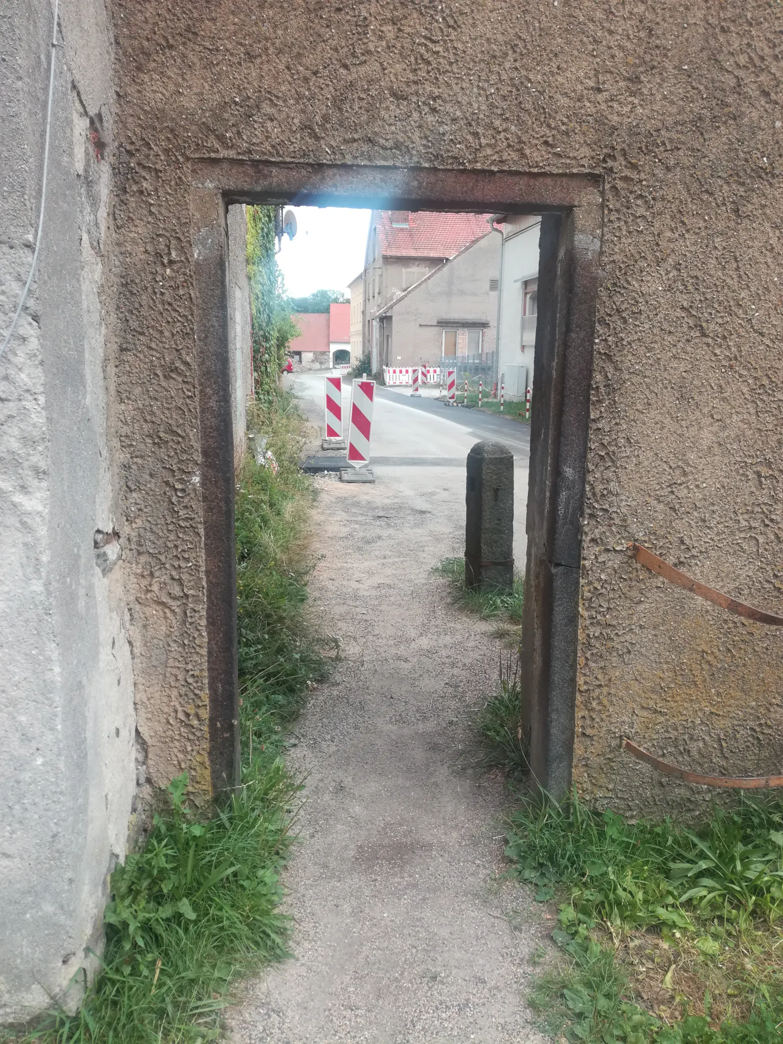 Blick durch Durchgang in Mauer auf Straße, trostlos aussehend.