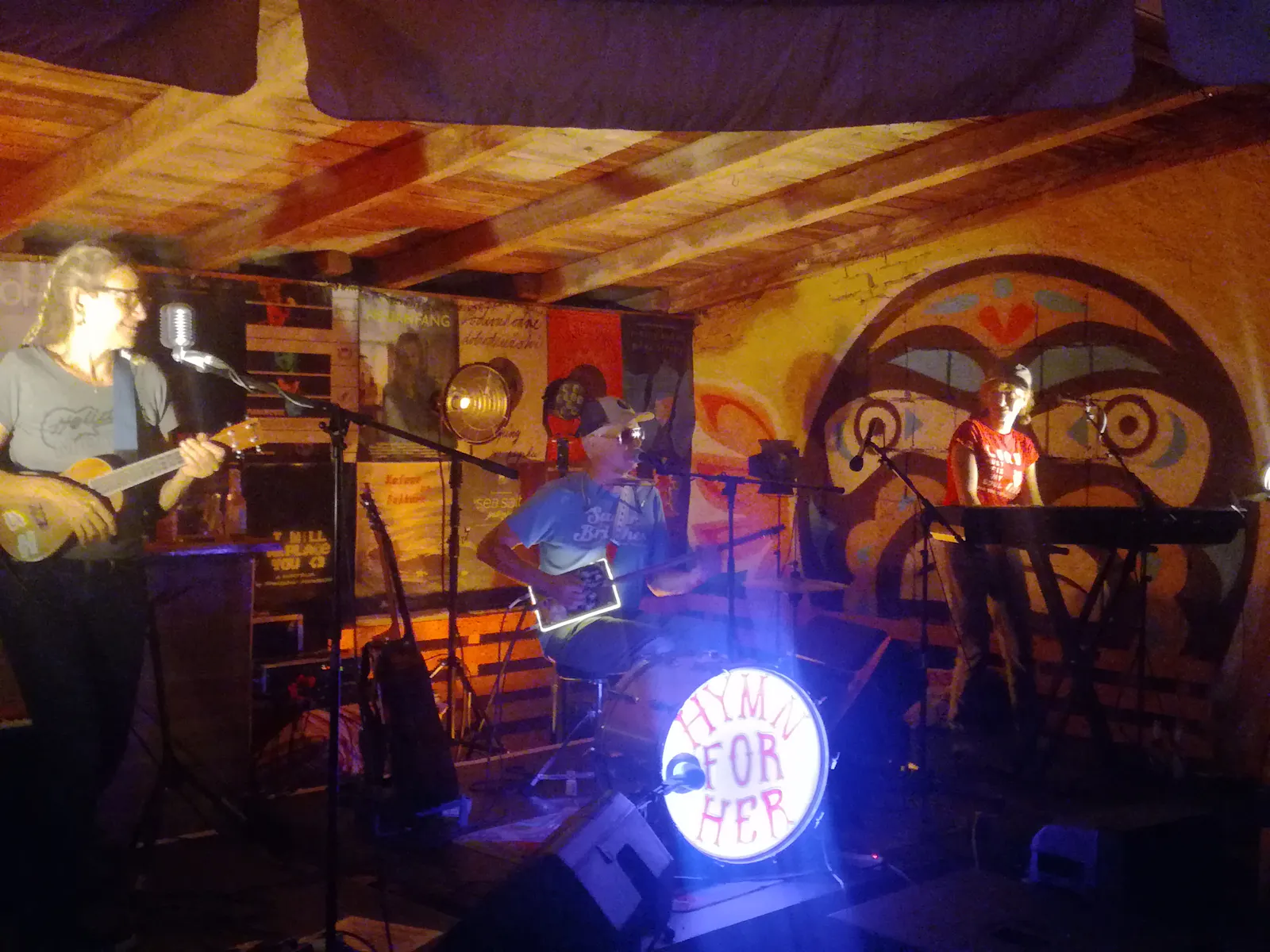 Hymn of her auf der Bühne. Rückwand mit Plakaten, Bassdrum leuchtet.