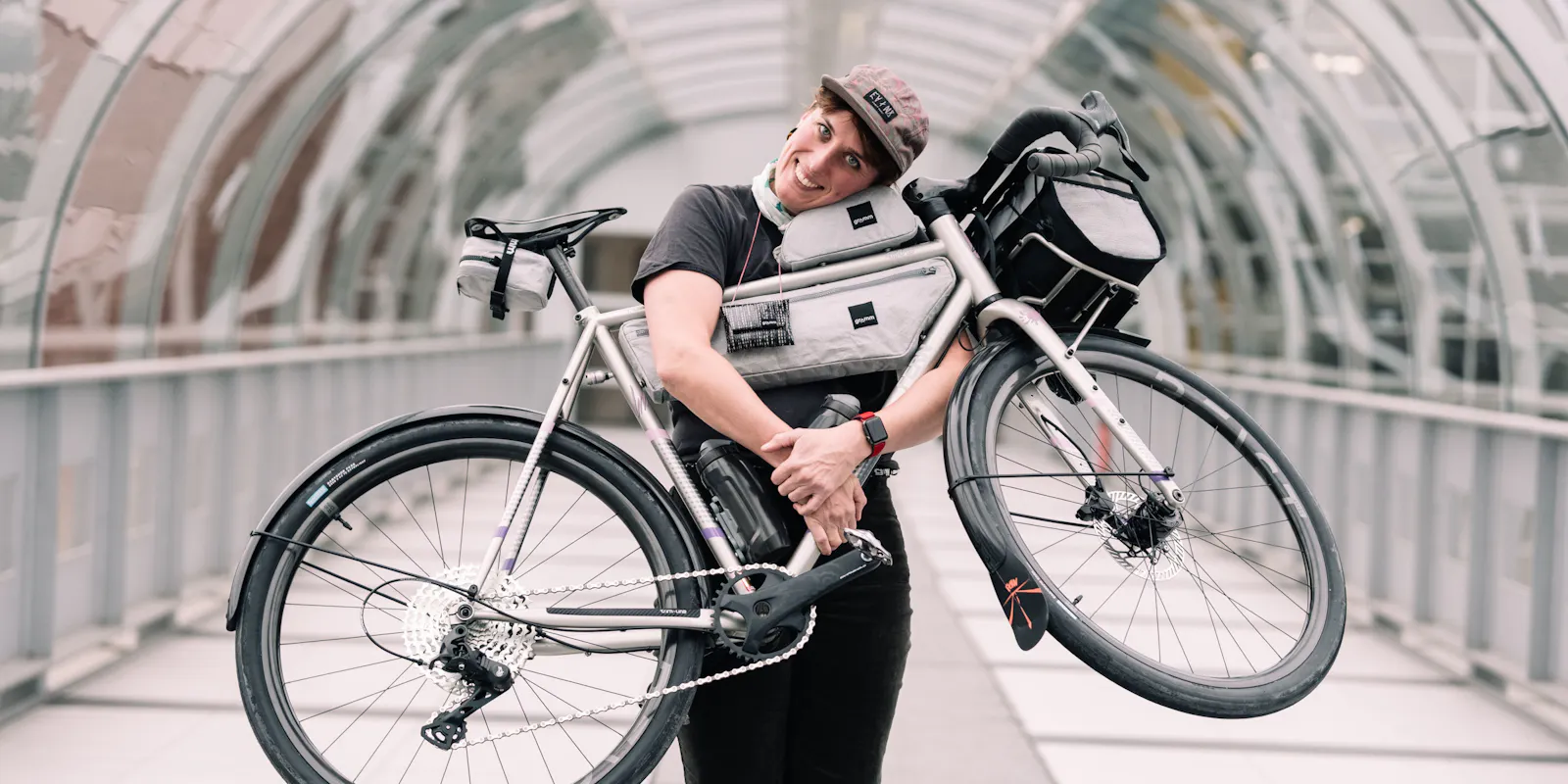 Tine Heil mit einem Fahrrad im Arm, daran Taschen ihrer Firma Gramm Tourpacking.