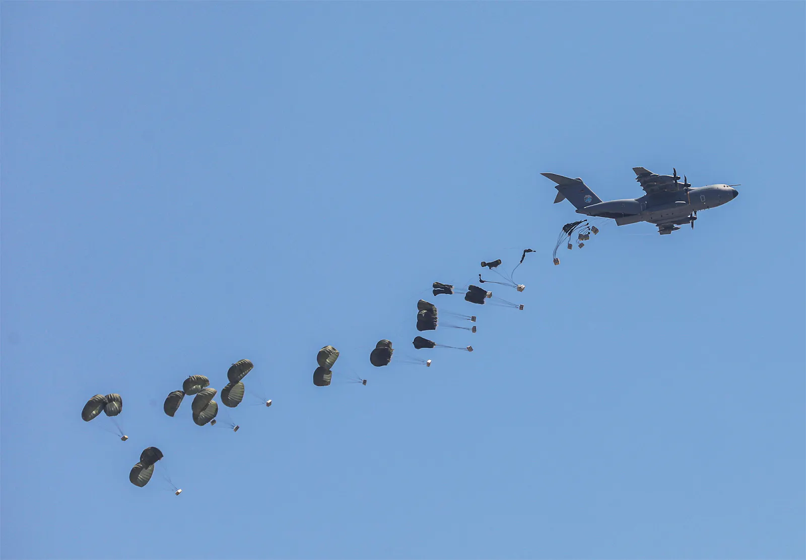 Paletten an Fallschirmen werden aus einem Flugzeug abgeworfen.