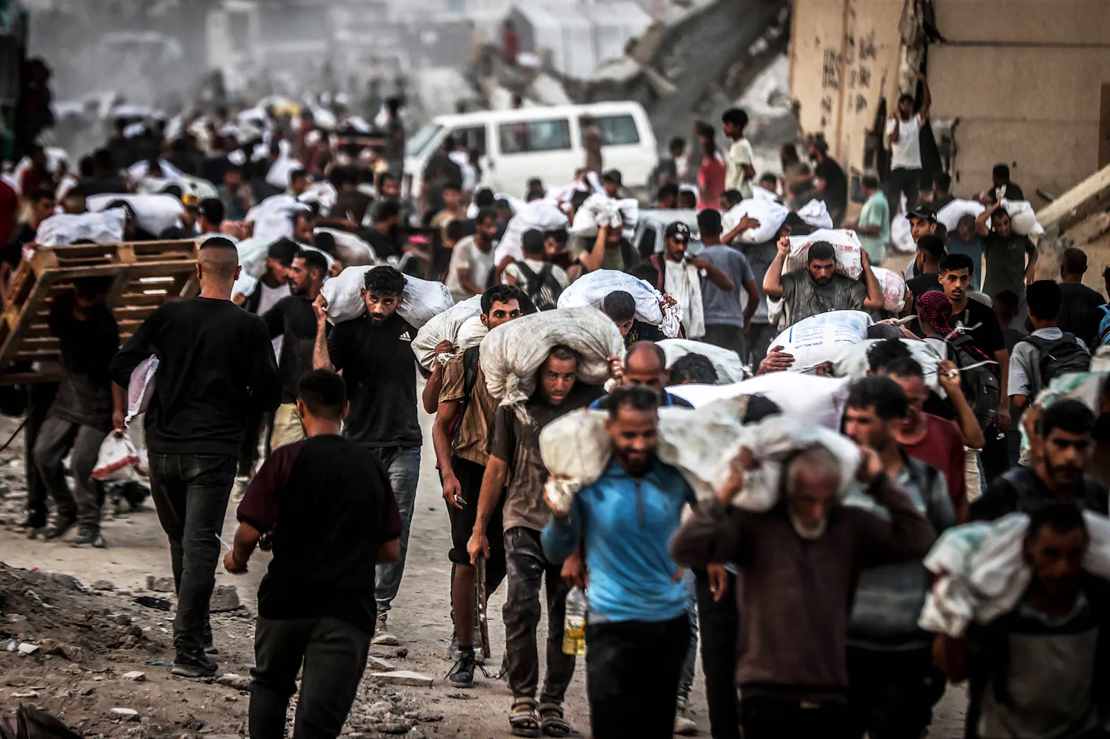 Ausschließlich junge Männer tragen Säcke mit Hilfslieferungen der UN weg. Im Hintergrund ein Fahrzeug der UN. Gaza-Stadt, 27.07.2025