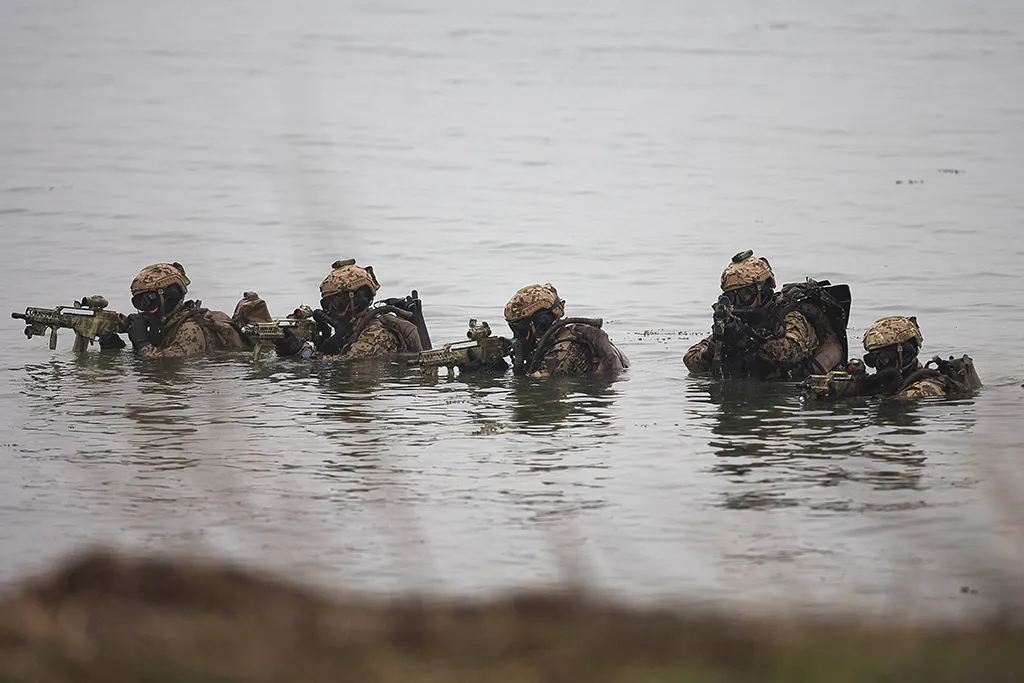 Deutsche Kampfschwimmer tauchen mit den Waffen im Anschlag aus dem Wasser auf.