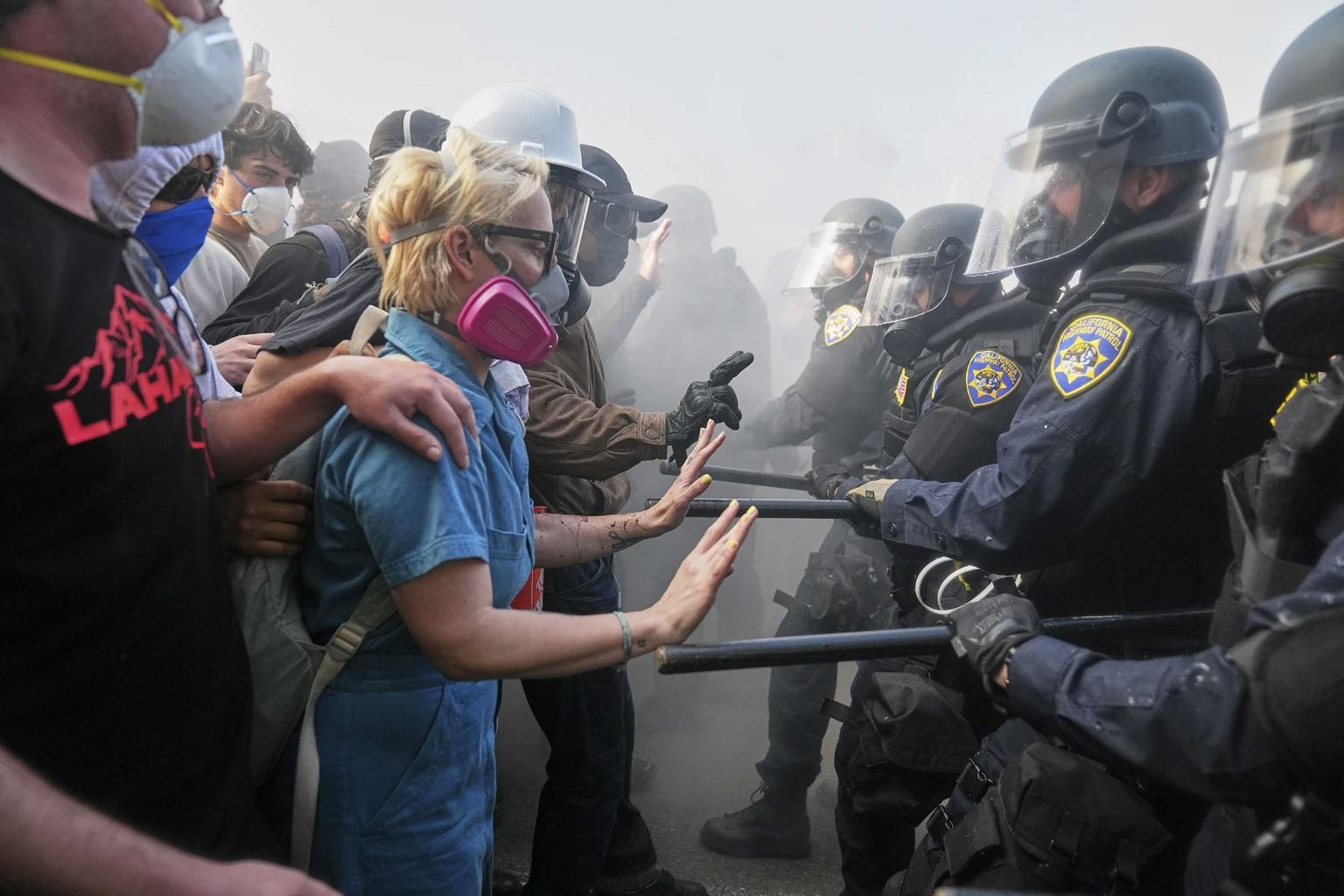 Polizei in Riot Gear und mit Schlagstöcken steht Protestierenden gegenüber, die die Hände erhoben haben. Bild aus Los Angeles