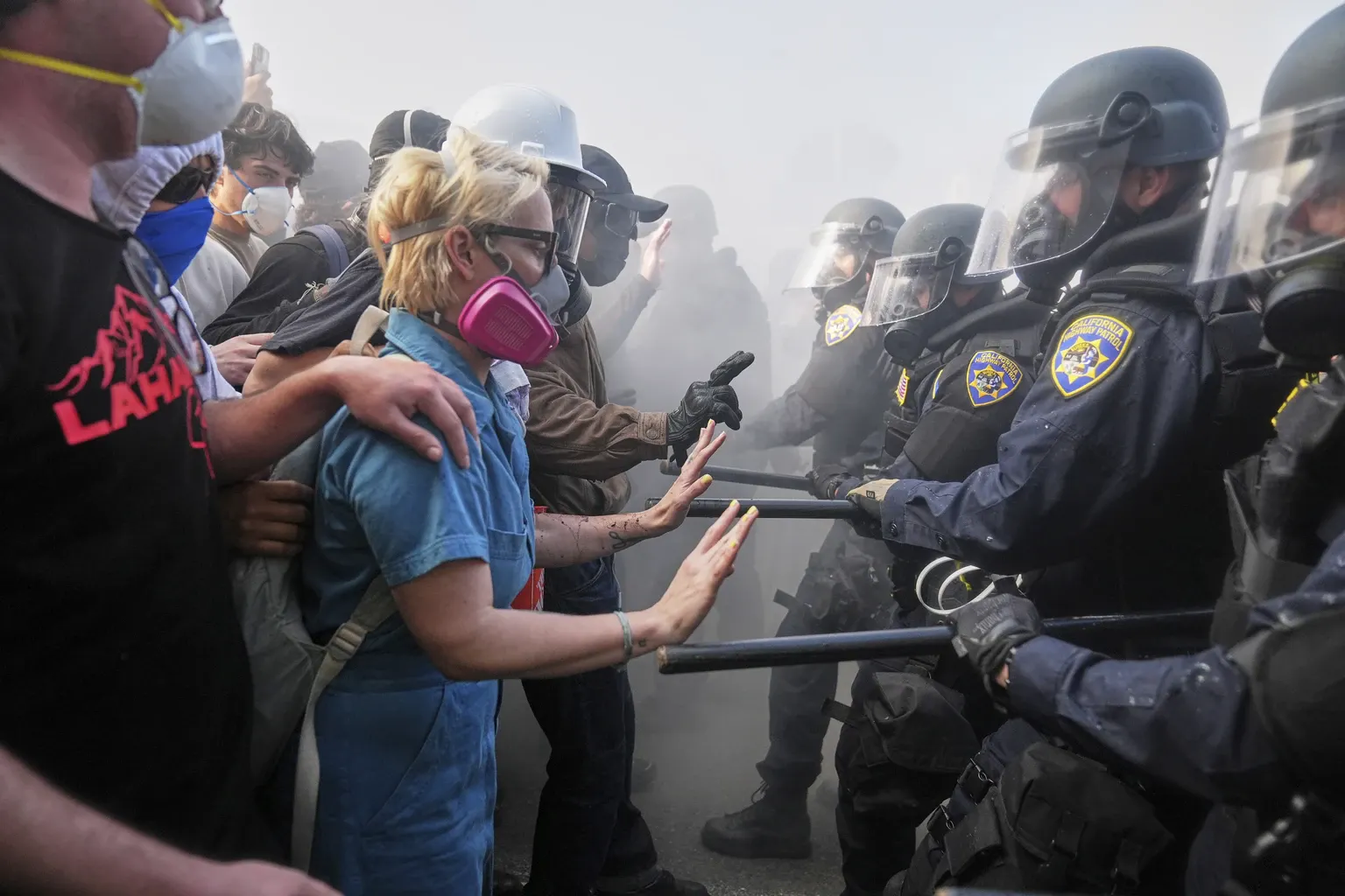 Polizei in Riot Gear und mit Schlagstöcken steht Protestierenden gegenüber, die die Hände erhoben haben. Bild aus Los Angeles