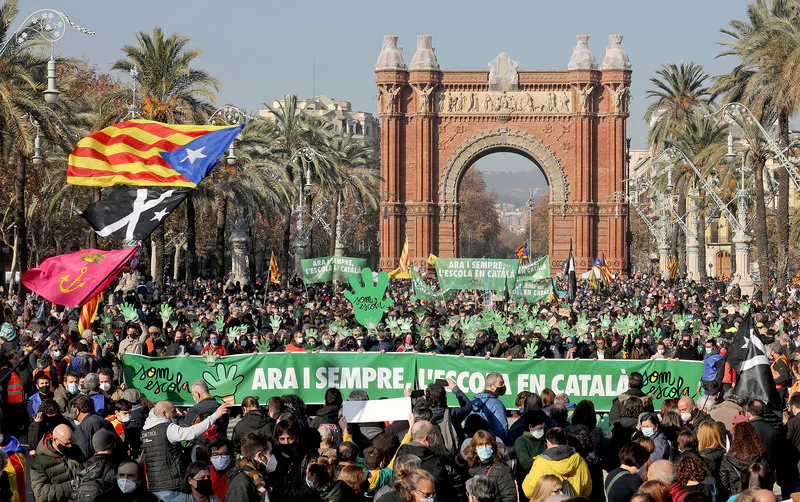 Eine Demonstration in Barcelona. Im Hintergund ist der Triumphbogen zu sehen, davor eine Menschenmenge mit einem Banner auf dem auf Katalanisch steht: "Jetzt und immer, Schule auf Katalanisch".