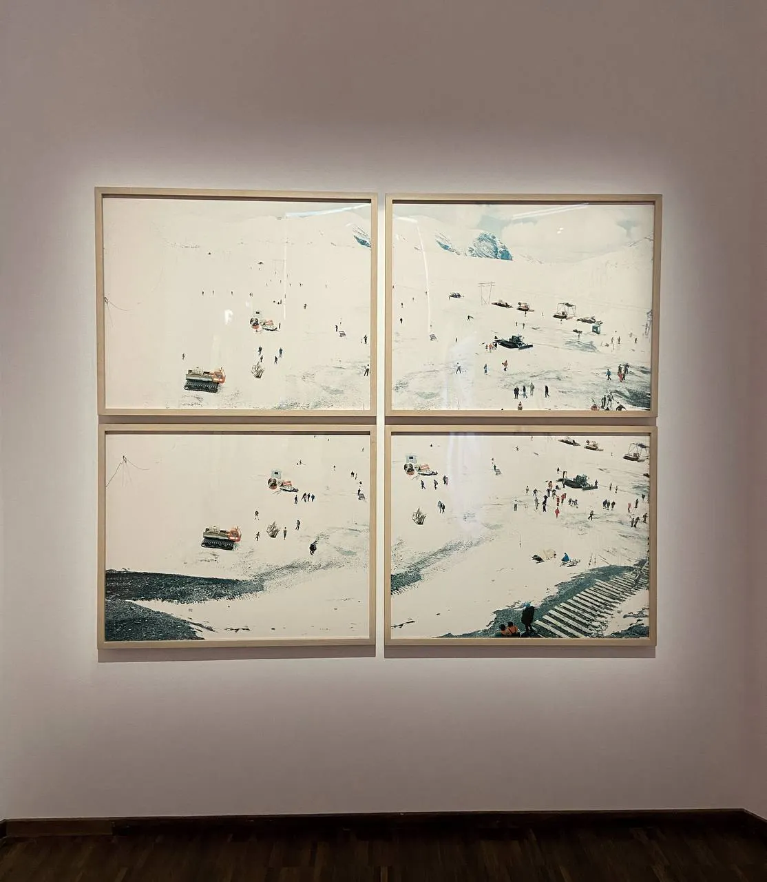 Ein Bild von vier Bildern aus der Ausstellung. Es zeigt eine Schneelandschaft mit SKifahrerinnen und -fahrern.