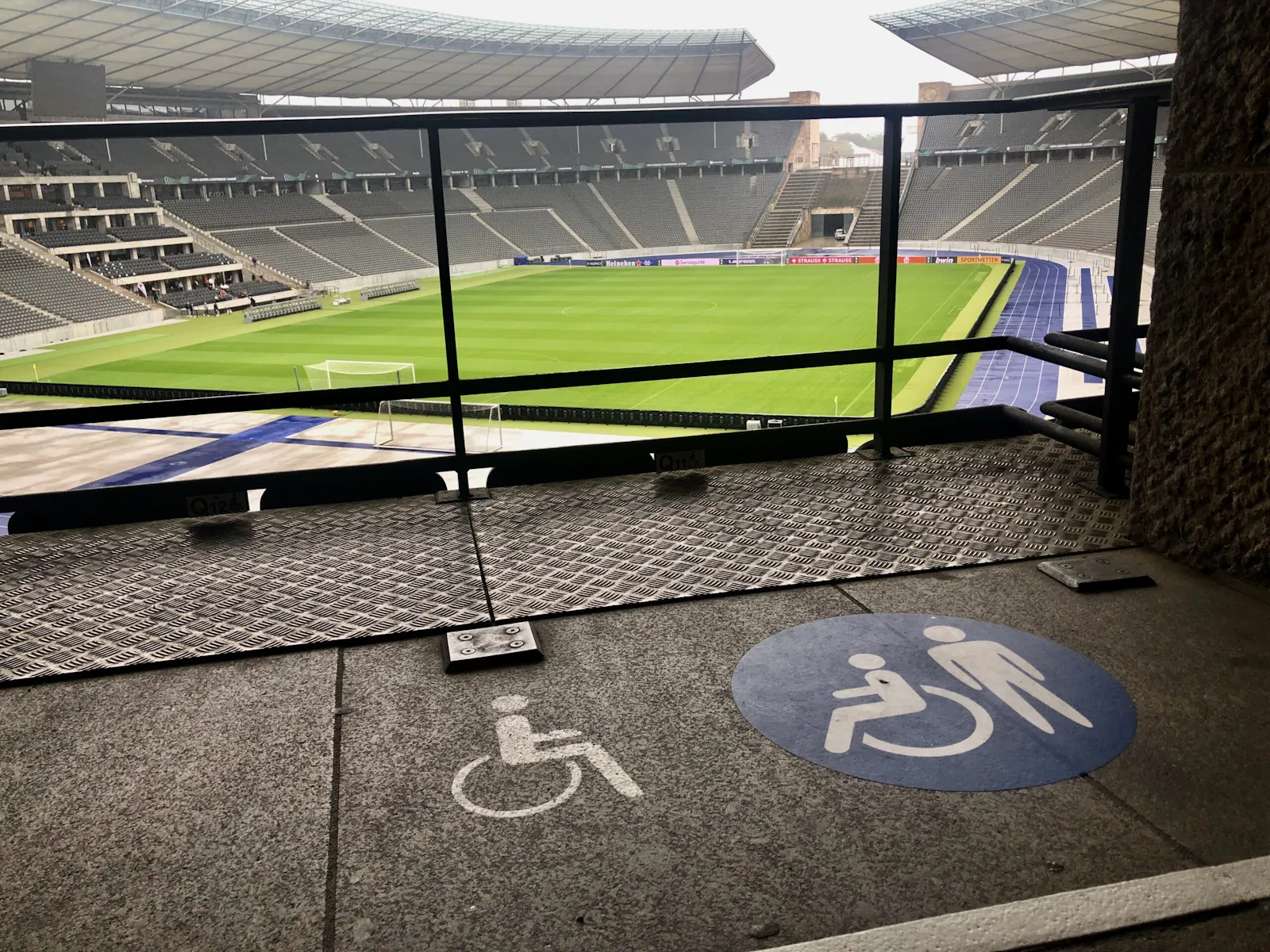 Blick ins Berliner Olympiastadion. Im Vordergrund sind Rollstuhlplätze zu sehen, die durch Piktogramme auf dem Boden klar gekennzeichnet sind.
