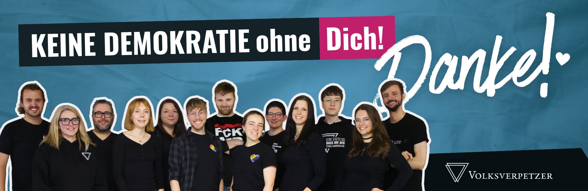 Keine Demokratie ohne Dich! als weiße Schrift auf dunkelblauem Balken, Dich! ist pink hinterlegt. In Handschrift: ein großes weißes Danke mit Herz. Unten links: ein Gruppenbild des 13-köpfigen Volksverpetzer-Teams. Unten rechts: Volksverpetzer-Logo. Der Hintergrund ist blau, mit Papiertextur.