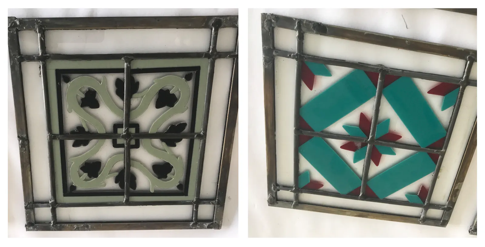 Quadratische Bleiglaselemente in Fliesengröße mit floralen Motiven. Links blassgrün und schwarz. Rechts türkis und rot.