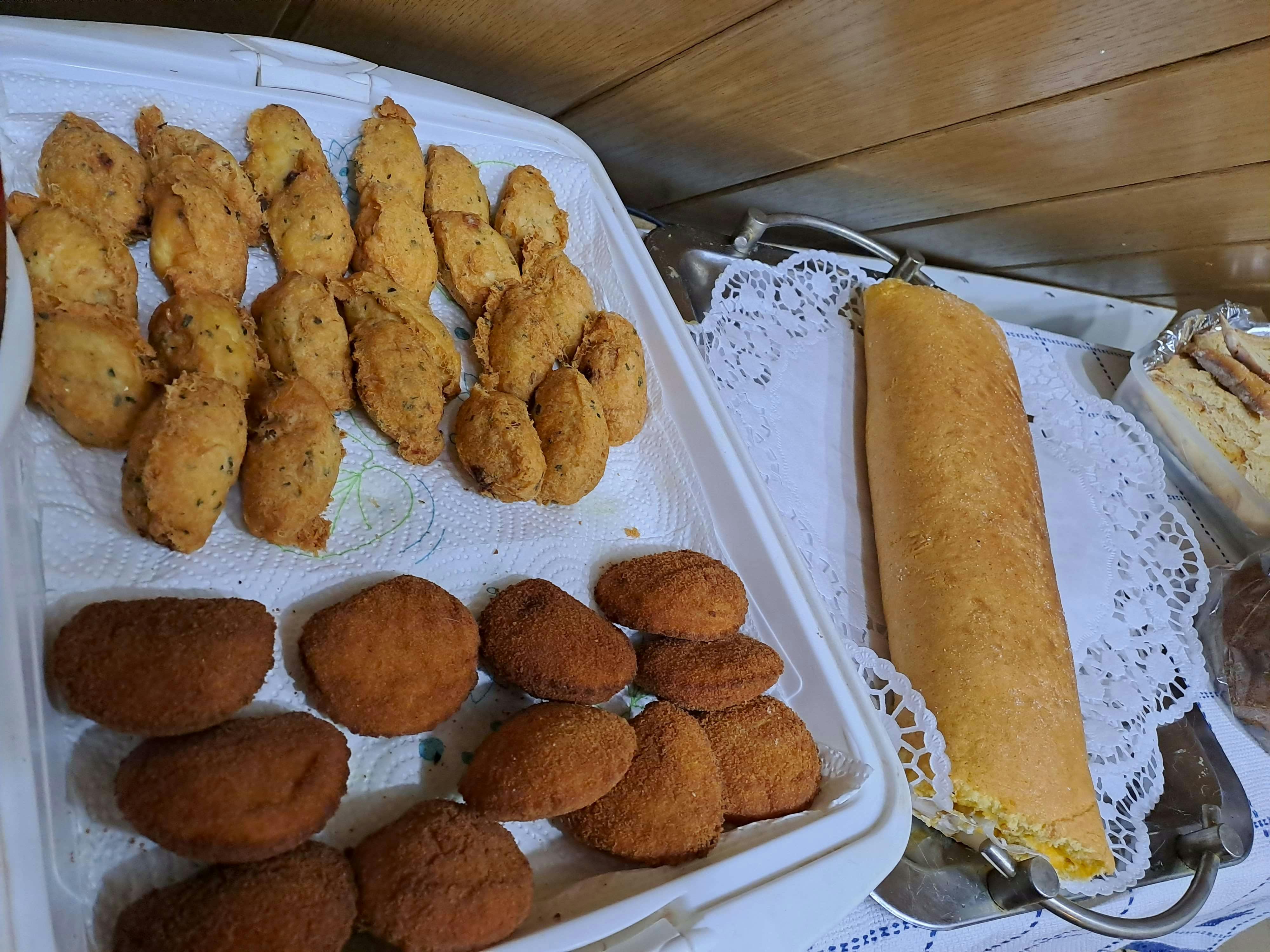 Weiße Servierplatte mit frittierten portugiesischen Snacks: längliche Stockfischkroketten und panierte Garnelentaschen.