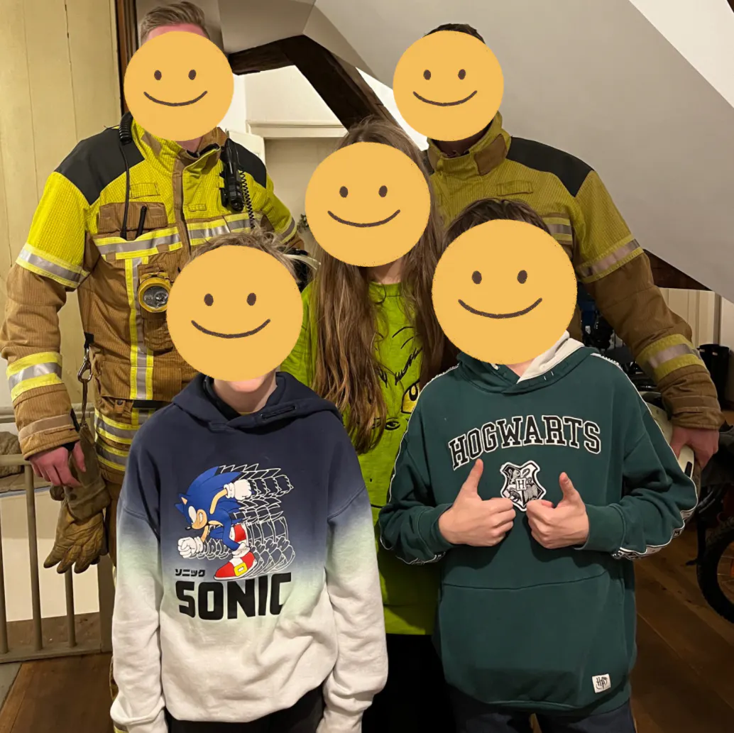 Gruppenfoto: Drei Kinder mit zwei Feuerwehr-Männern im Treppenhaus aufgenommen.