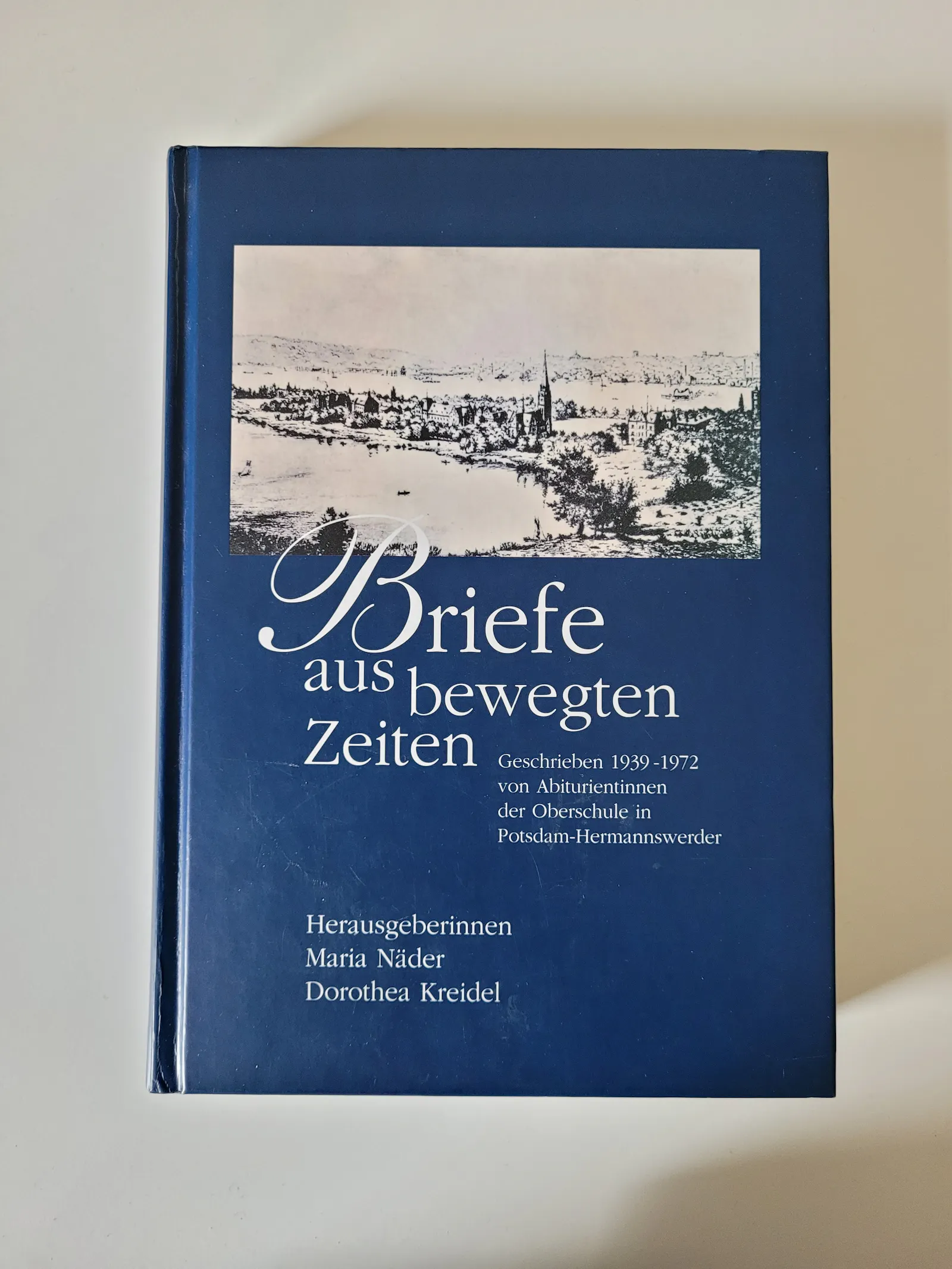 Blauer Buchumschlag mit dem Schwarz-weiß-Bild eines Dorfes am Wasser und dre Aufschrift: "Briefe aus bewegten Zeiten. Geschrieben 1939-1972 von Abiturientinnen der Oberschule in Potsdam-Hermannswerder. Herausgeberinnen Maria Näder, Dorothea Kreidel"