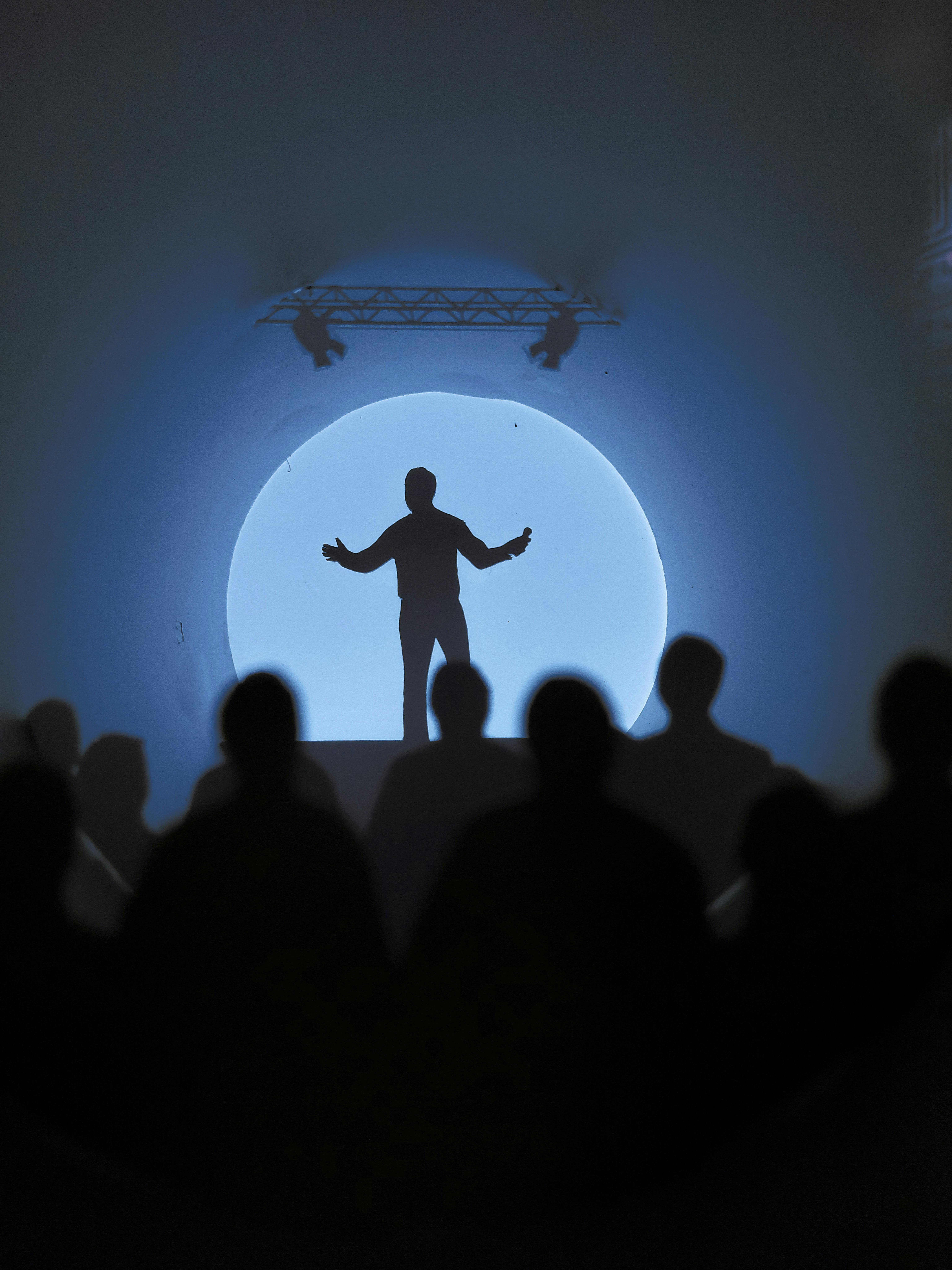 Die Silhouette eines Mannes auf einer Bühne vor einer Menschenmenge.