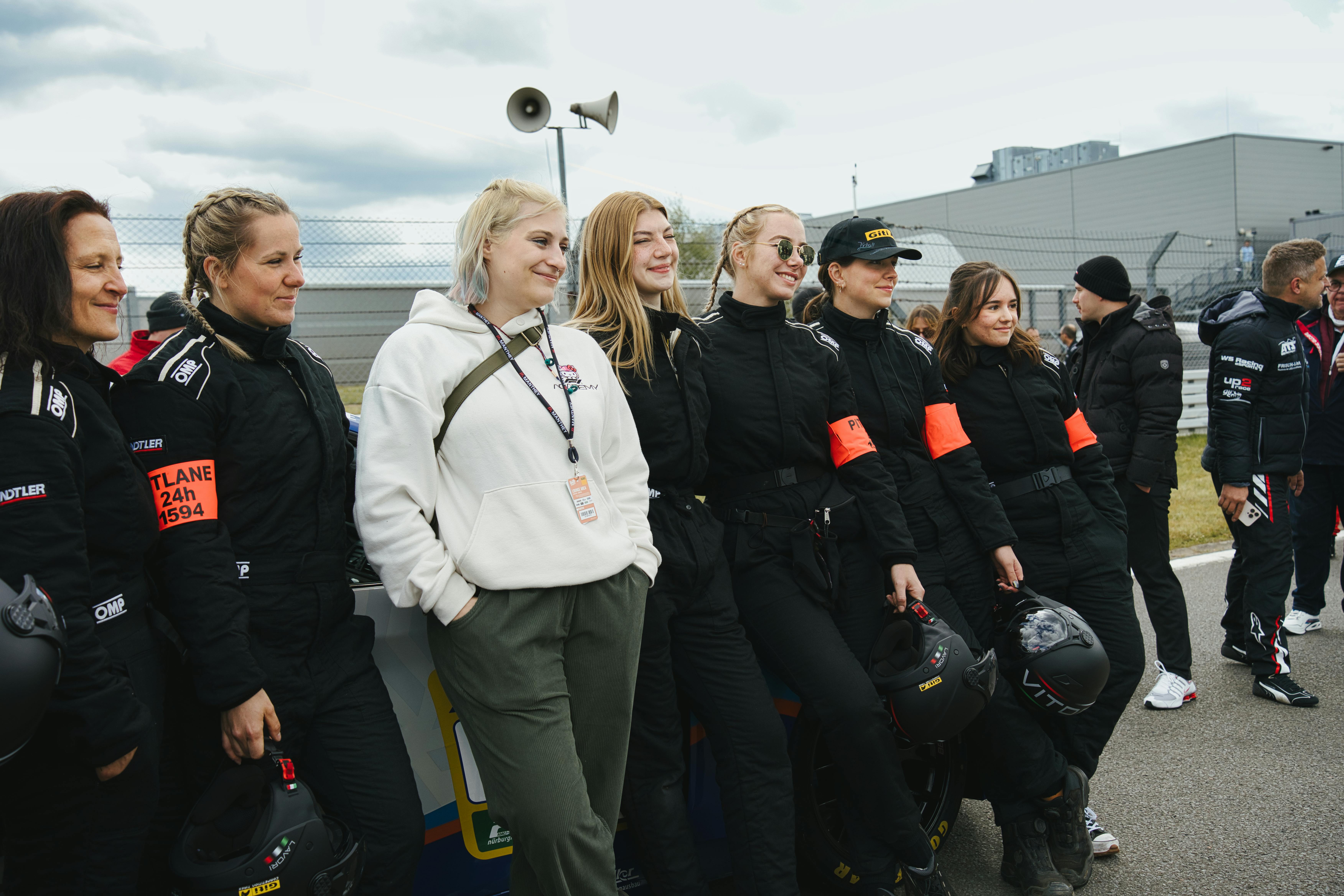 Carconny an ein Auto gelehnt mit einer Gruppe von jungen Frauen, Mechanikerinnen des Girls Only Teams
