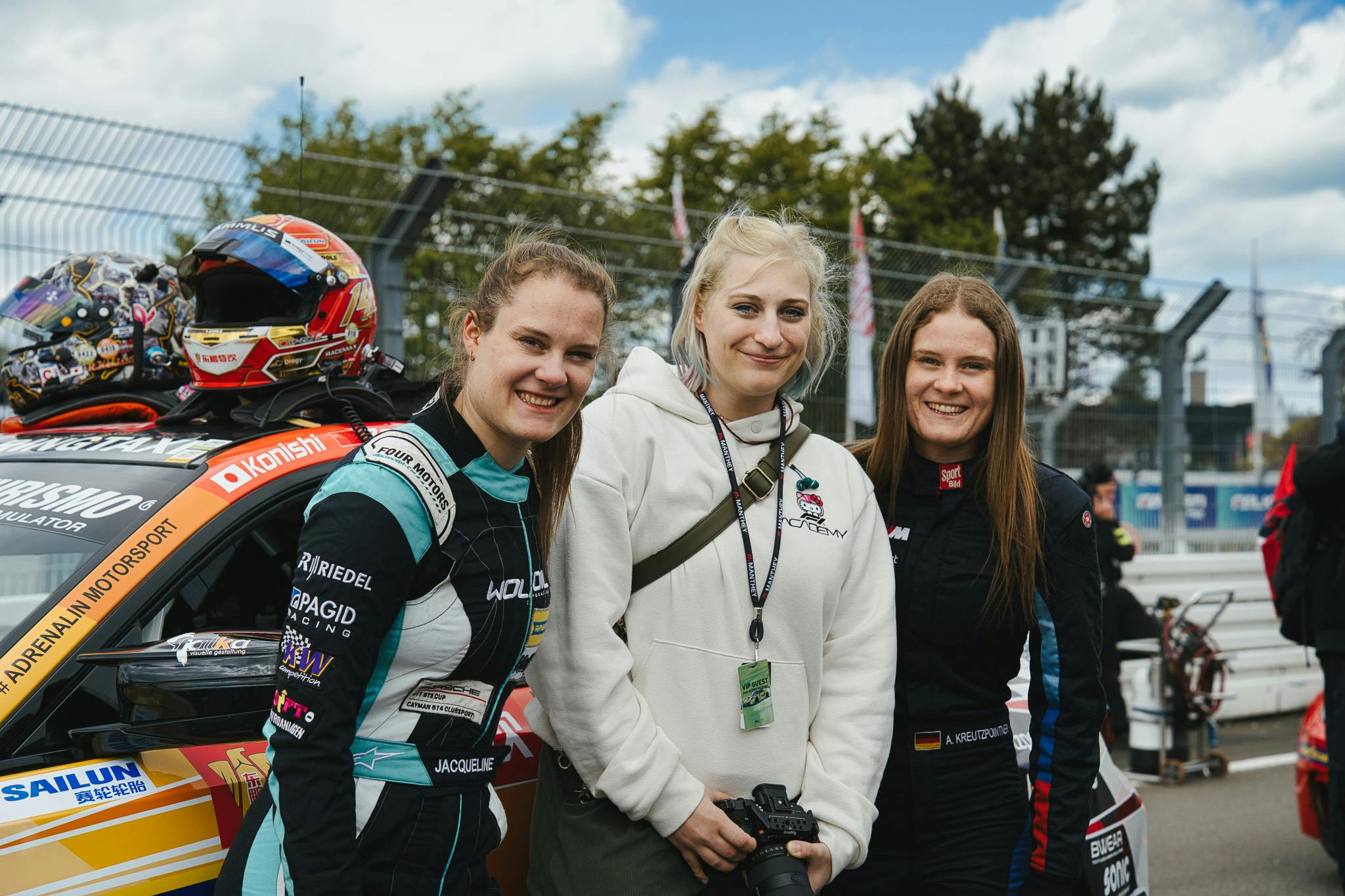 Carconny mit den zwei Rennfahrerinnen Alesia und Jacqueline Kreutzpointner vor ihrem Rennauto, auf dem Auto liegt ein Helm