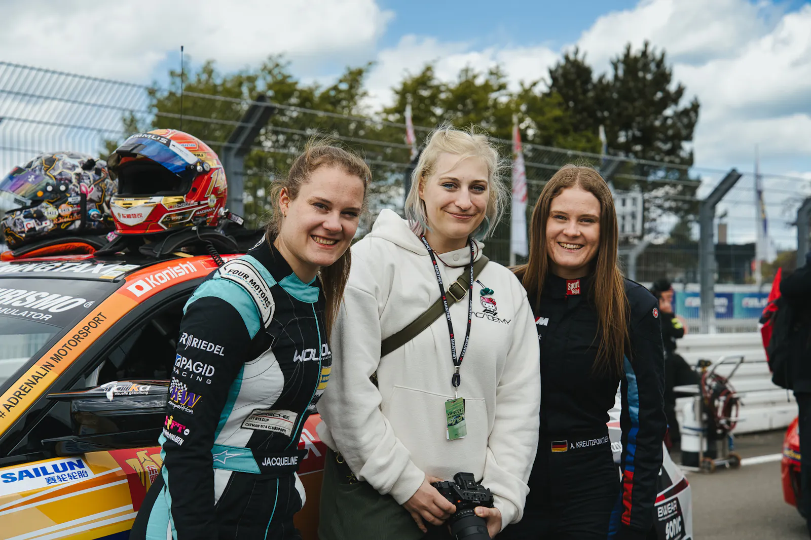 Carconny mit den zwei Rennfahrerinnen Alesia und Jacqueline Kreutzpointner vor ihrem Rennauto, auf dem Auto liegt ein Helm