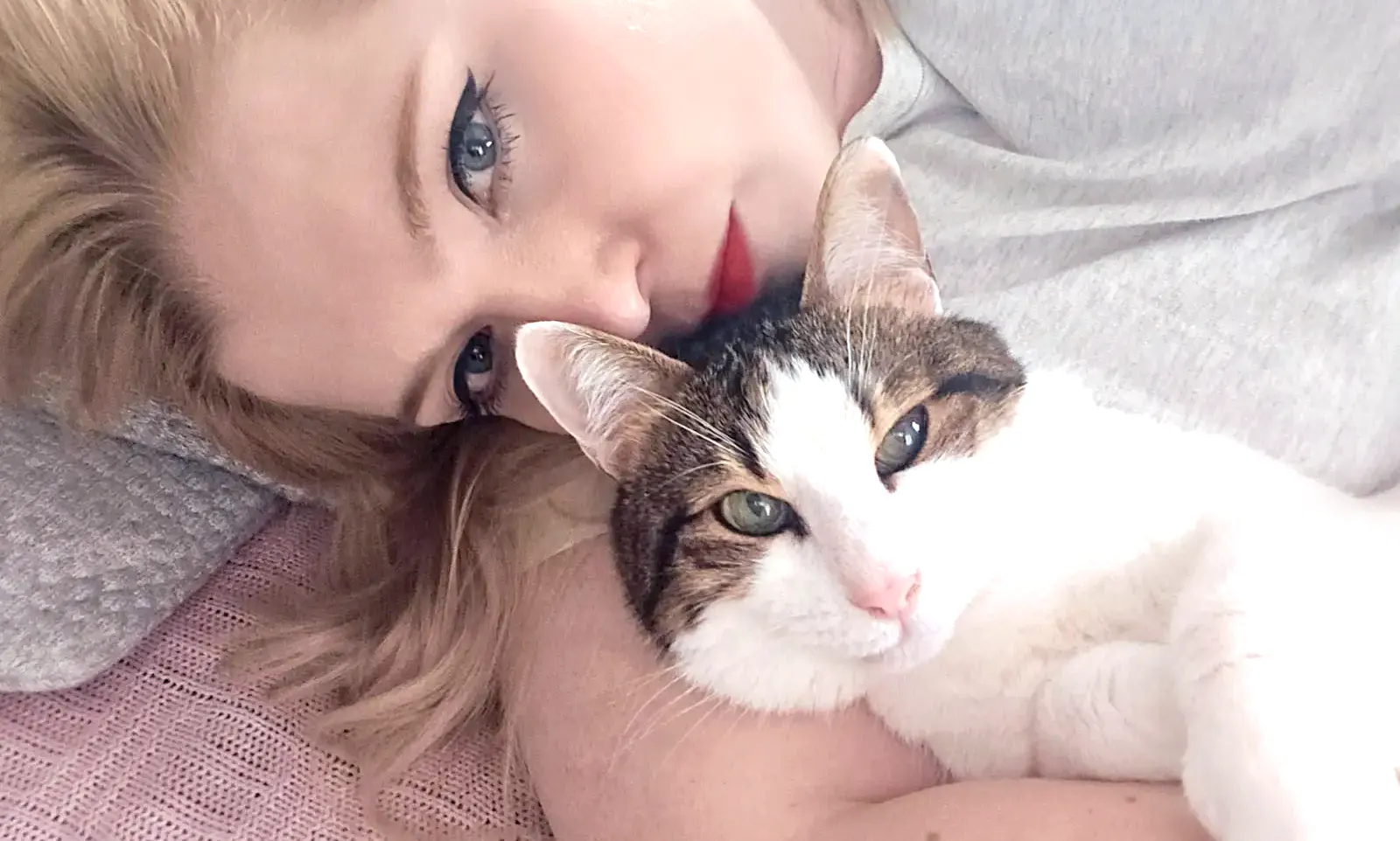 Rieke liegt mit ihrem Kater Ambrose kuschelnd auf dem Sofa.