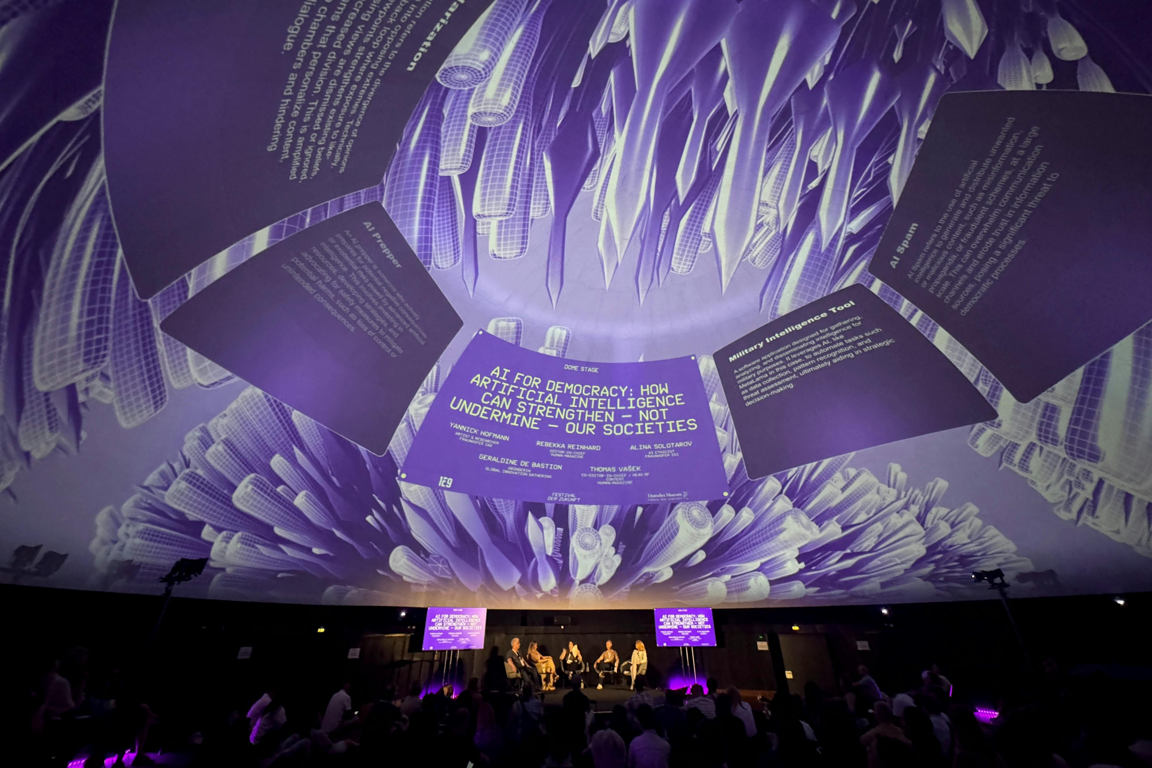 Ein mit fünf Personen besetztes Festival-Podium im stillgelegten Planetarium des Deutschen Museums. Die mit Projektionen bespielte runde Kuppel zeit außerdem Infokästen mit Text an.