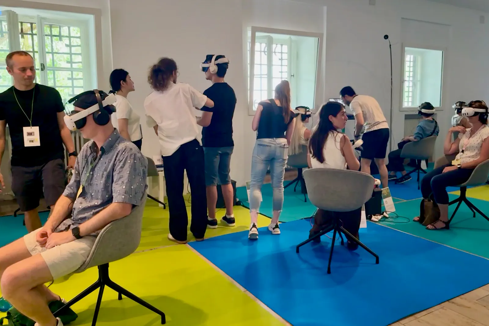 Menschen mit VR-Brillen sitzen und stehen in einem Raum.
