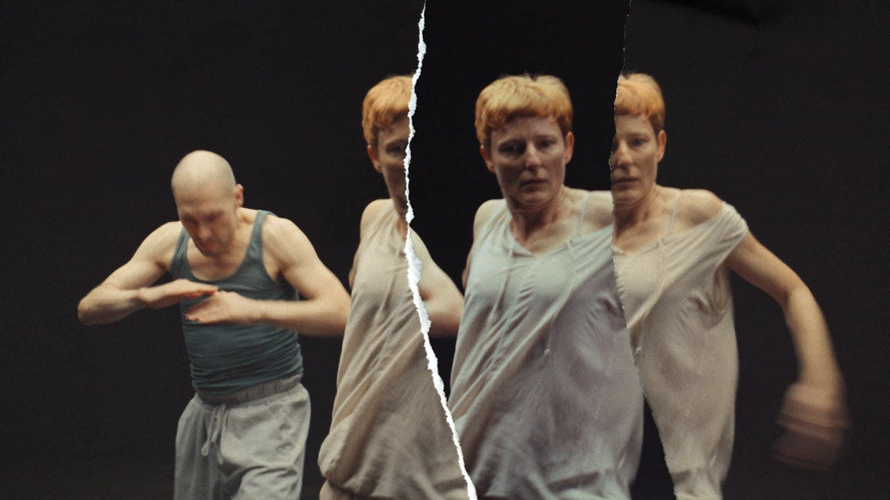 Filmstill aus dem Film Fassaden. Abgebildet sind eine Tänzerin und ein Tänzer in Bewegung. Über das Bild zieht sich ein Riss. Die Tänzerin ist mehrmals zu sehen, so als wären verschiedene zerrissene Fotos übereinander gelegt worden.