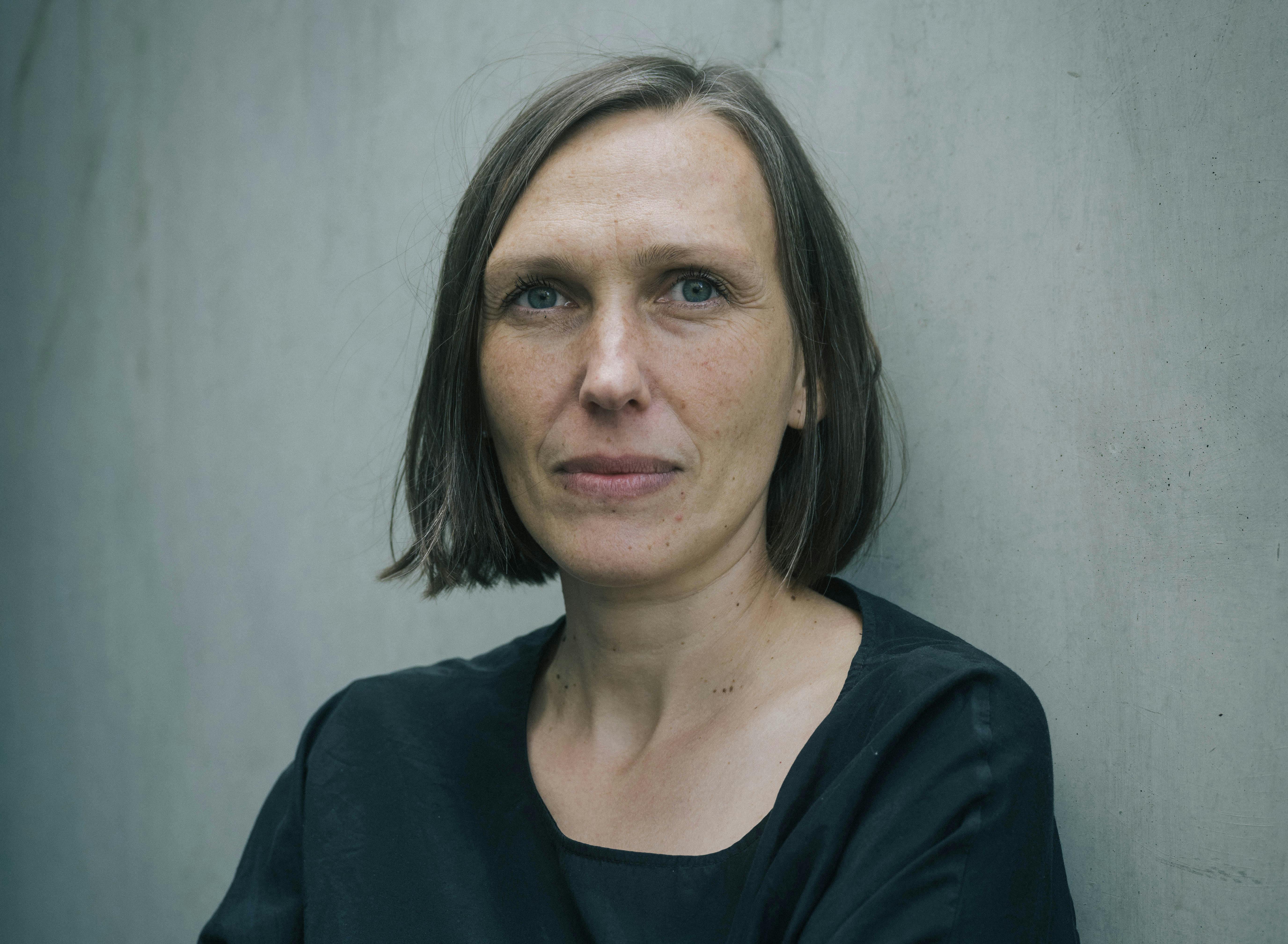 Portrait-Aufnahme der Regisseurin Alica Cyranek vor einer grauen Wand.