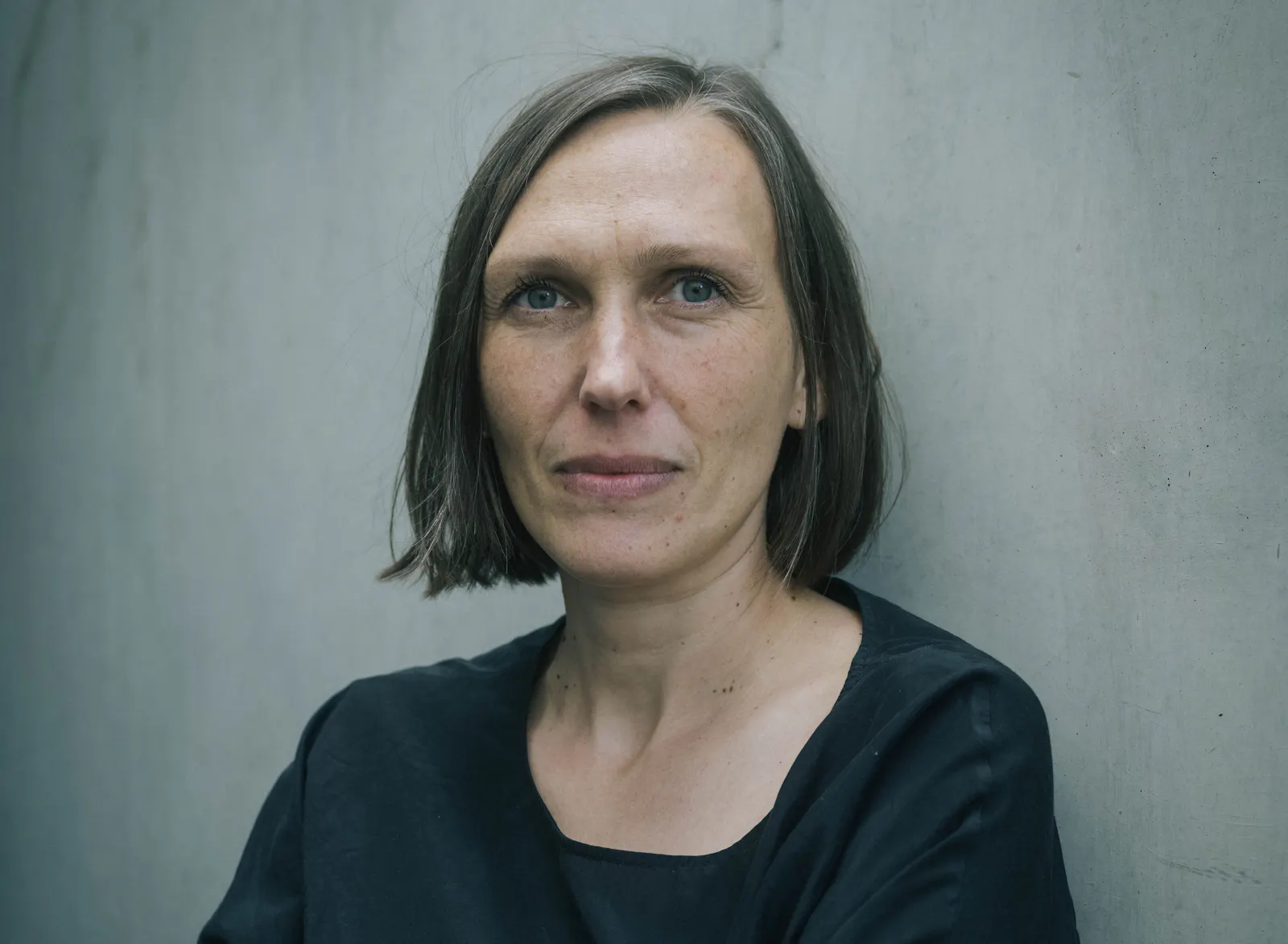 Portrait-Aufnahme der Regisseurin Alica Cyranek vor einer grauen Wand.