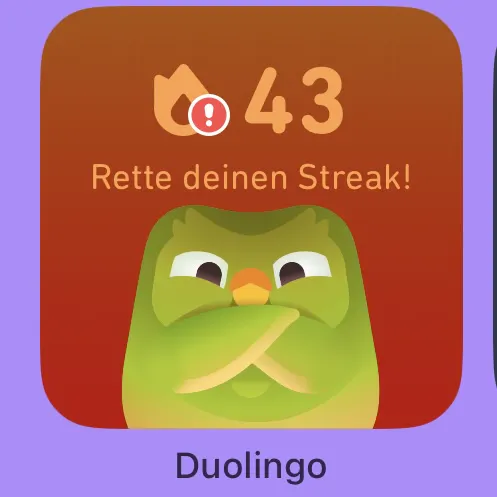 Duolingo-Button mit Eule, die die Arme verschränkt hat und dämonisch dreinblickt