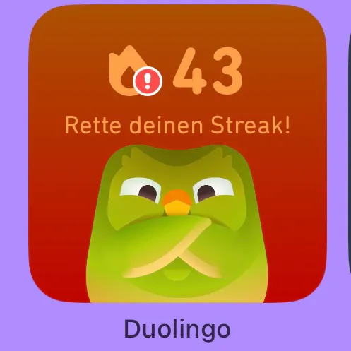 Duolingo-Button mit Eule, die die Arme verschränkt hat und dämonisch dreinblickt