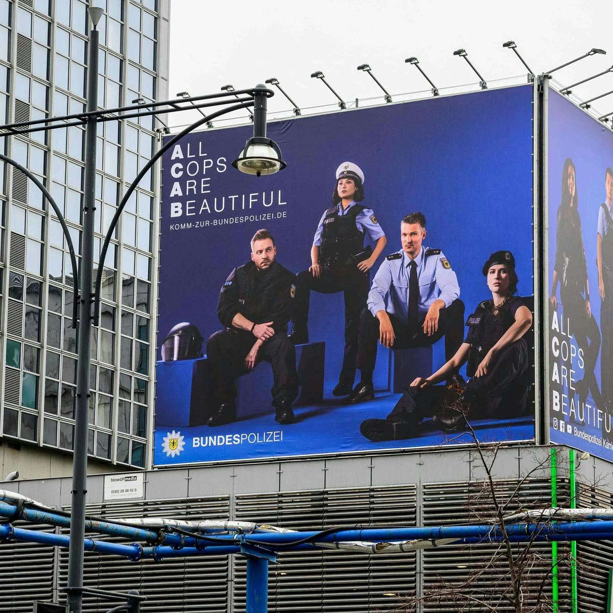 Foto eines riesigen Werbebanners irgendwo in Berlin. Vier Bundespolizist*innen in unterschiedlicher Kluft blicken mit reichlich Attitüde in die Kamera. Oben links steht die Losung
All
Cops
Are
Beautiful
KOMM zur Bundespolizei