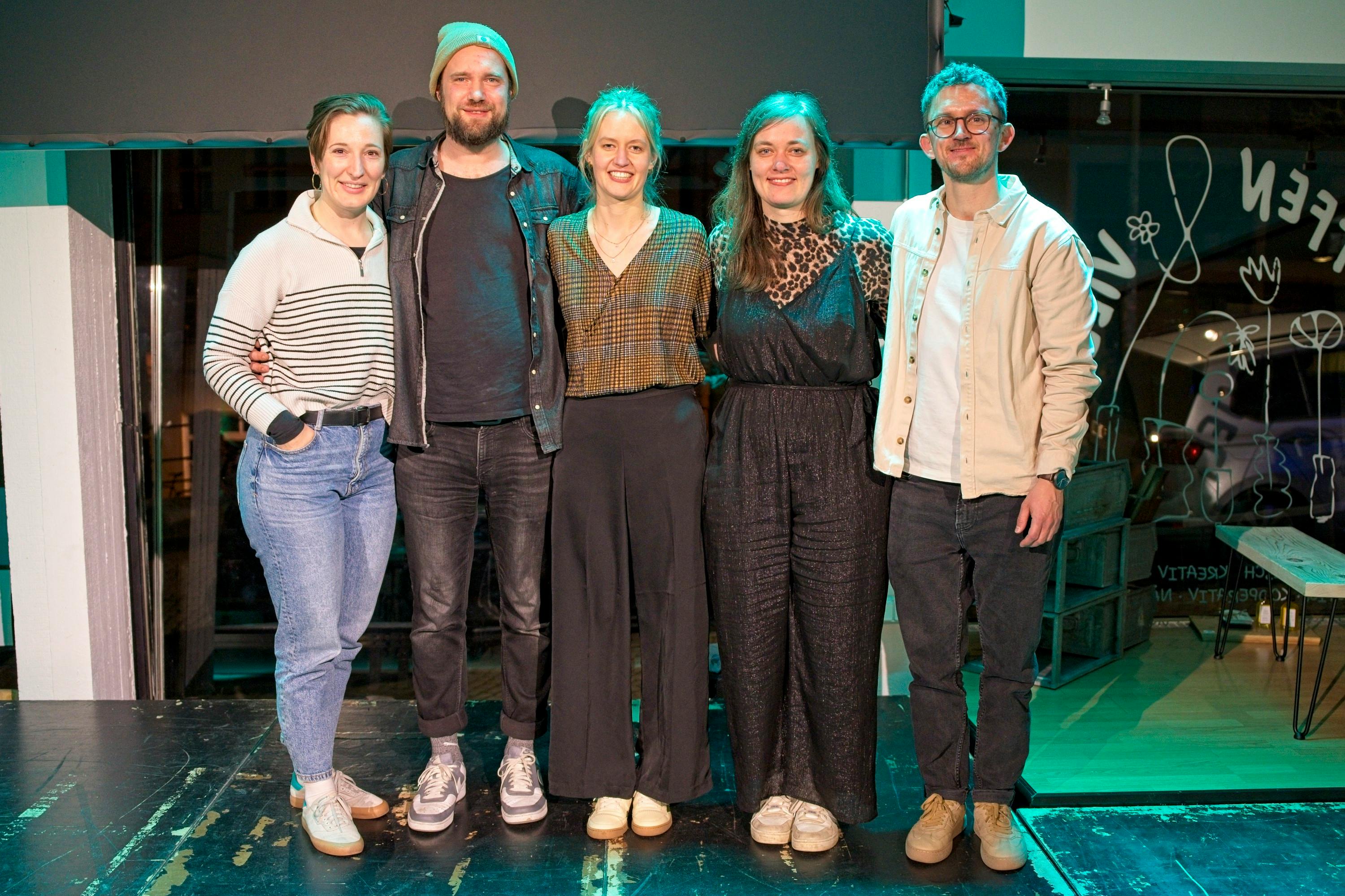 Das Foto zeigt Tabitha Hanan, Marco Michalzik, Leah Weigand, Jasmin Brückner und Tobias Fleck, wie sie nach der Buchpremiere von Leah gemeinsam Arm in Arm auf der Bühne stehen.