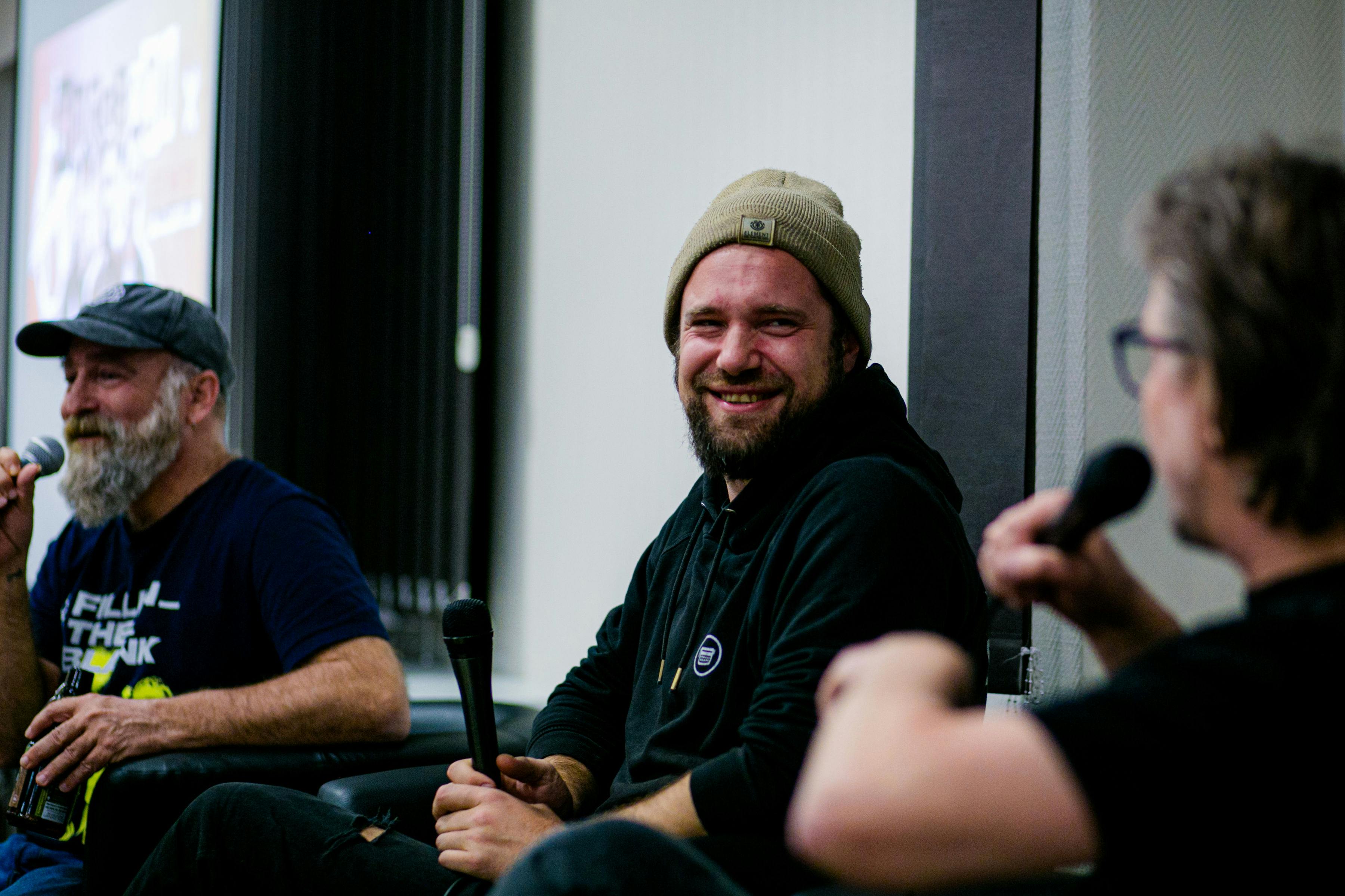 Das Foto zeigt Jay, Marco und Gofi beim Live Talk während der Hossa Con. Alle drei lachen und haben Mikrofone in der Hand.
