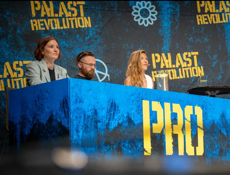 Foto vom Tisch auf der Bühne, an dem die Pro-Seite sitzt. Von links nach rechts: Philine Edbauer, morf mit meinung, Martyna Linartas