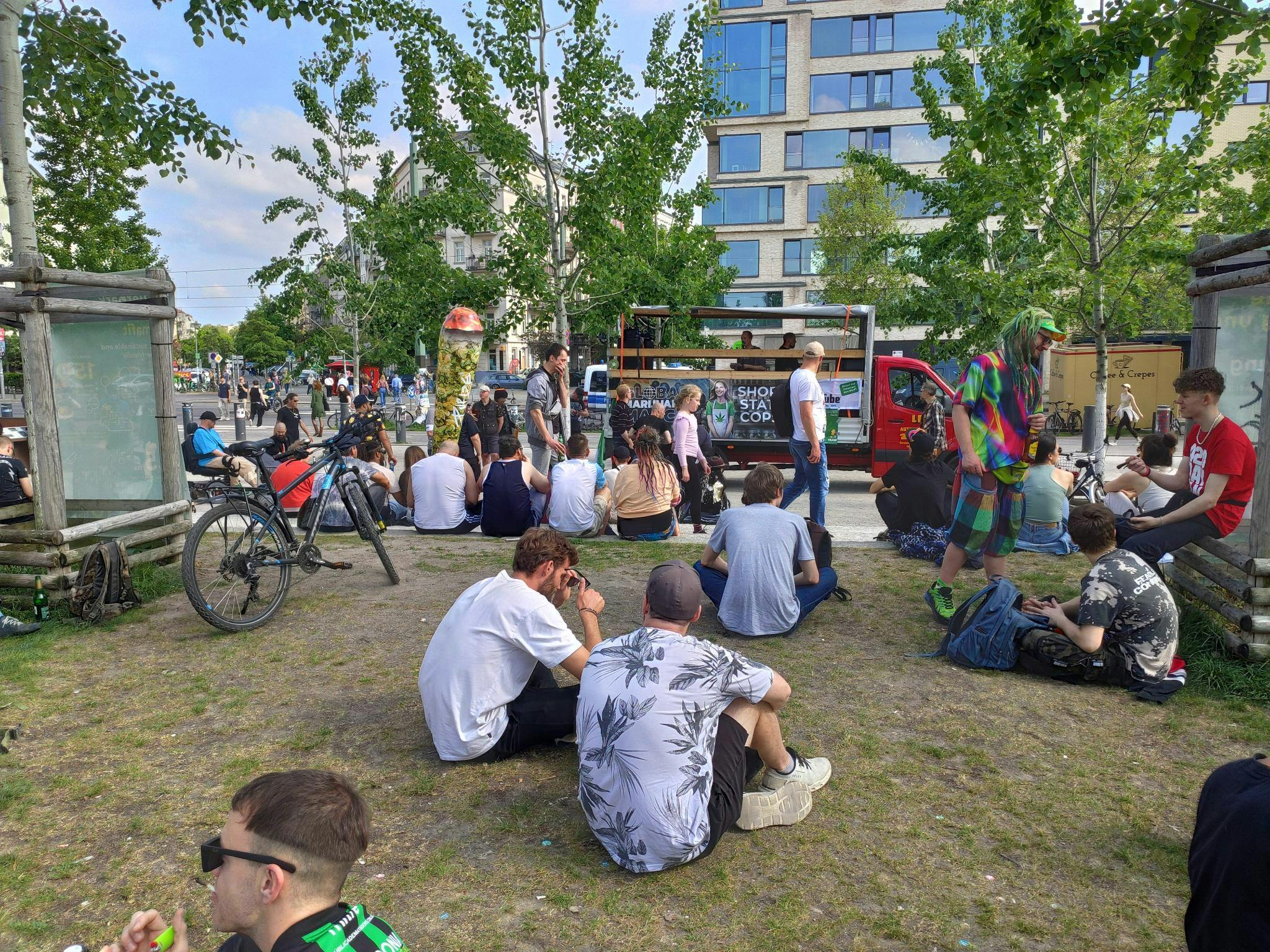 Demonstrant*innen sitzen und stehen im Mauerpark in Gruppen vorm Lautsprecherwagen