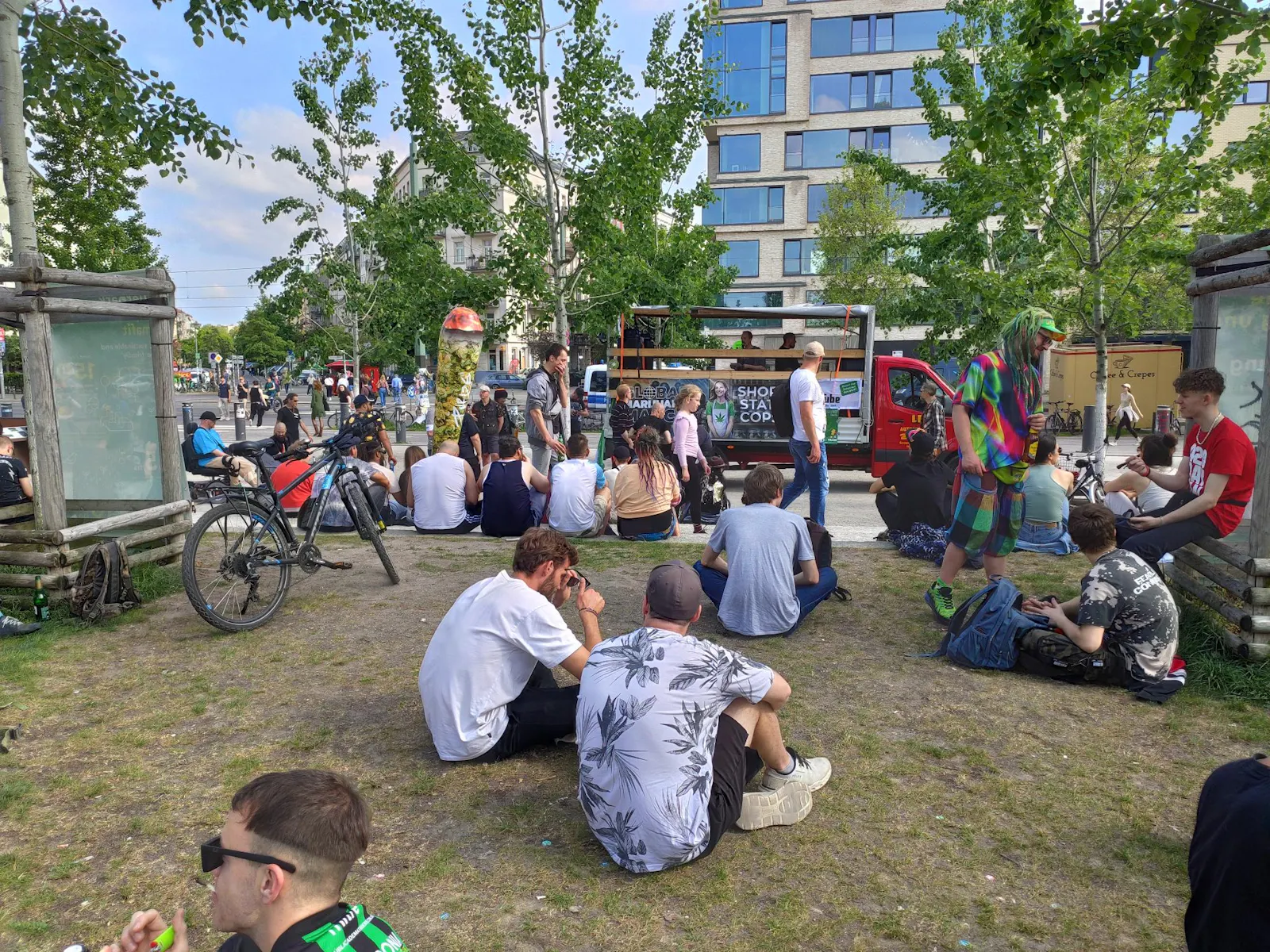 Demonstrant*innen sitzen und stehen im Mauerpark in Gruppen vorm Lautsprecherwagen