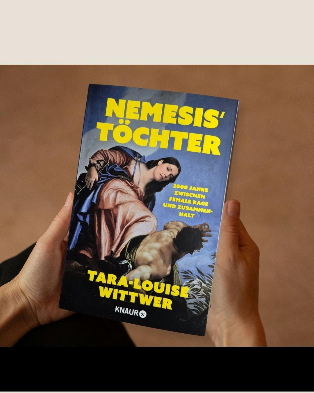 Das Buch Nemesis' Töchter wird in beiden Händen gehalten.
