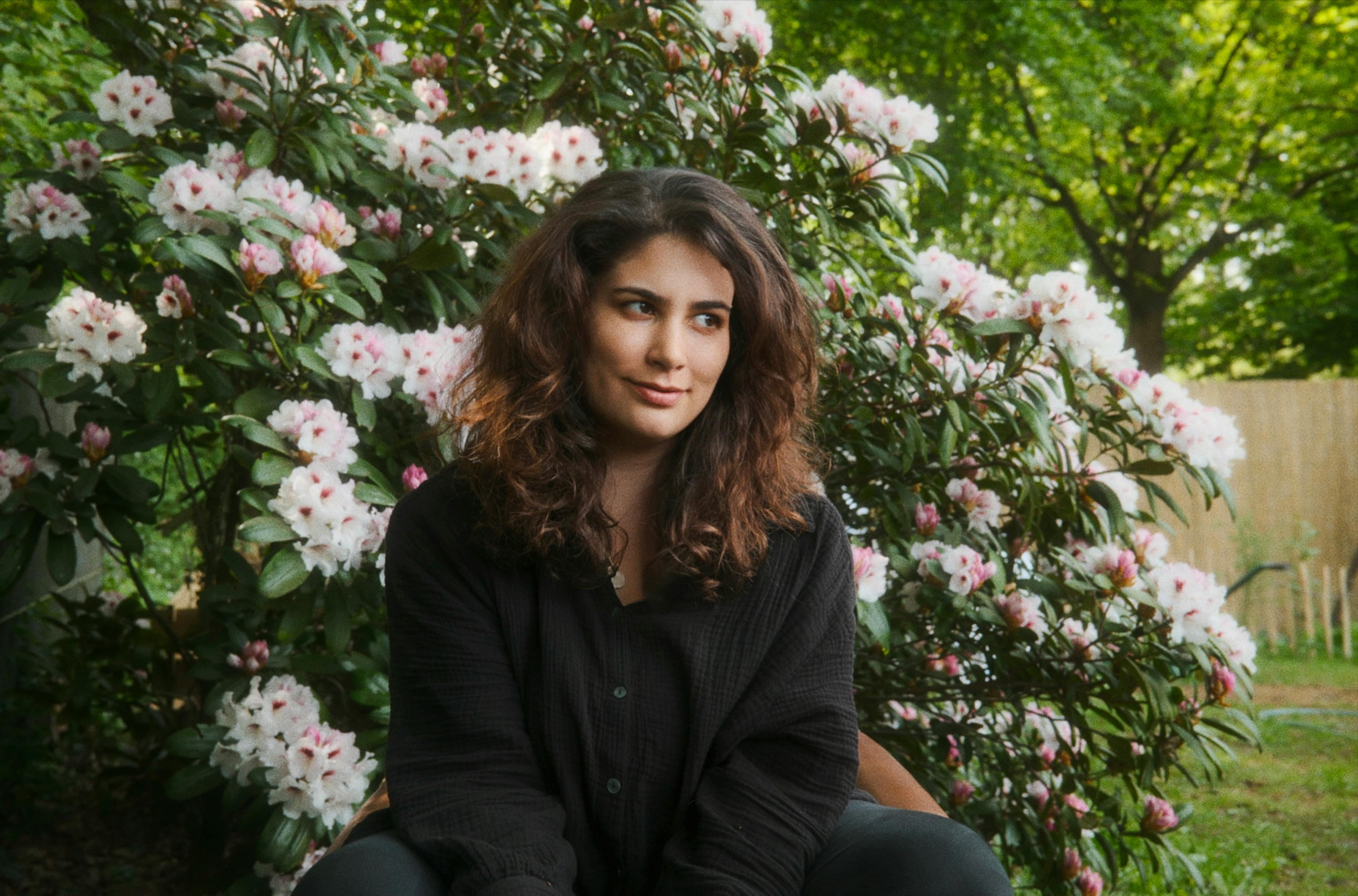 Jasmin sitzt vor einem blühenden Rhododendron