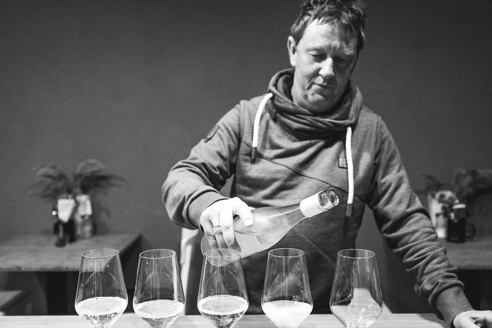Weinhändler Axel Krüger gießt Weißwein in fünf Gläser