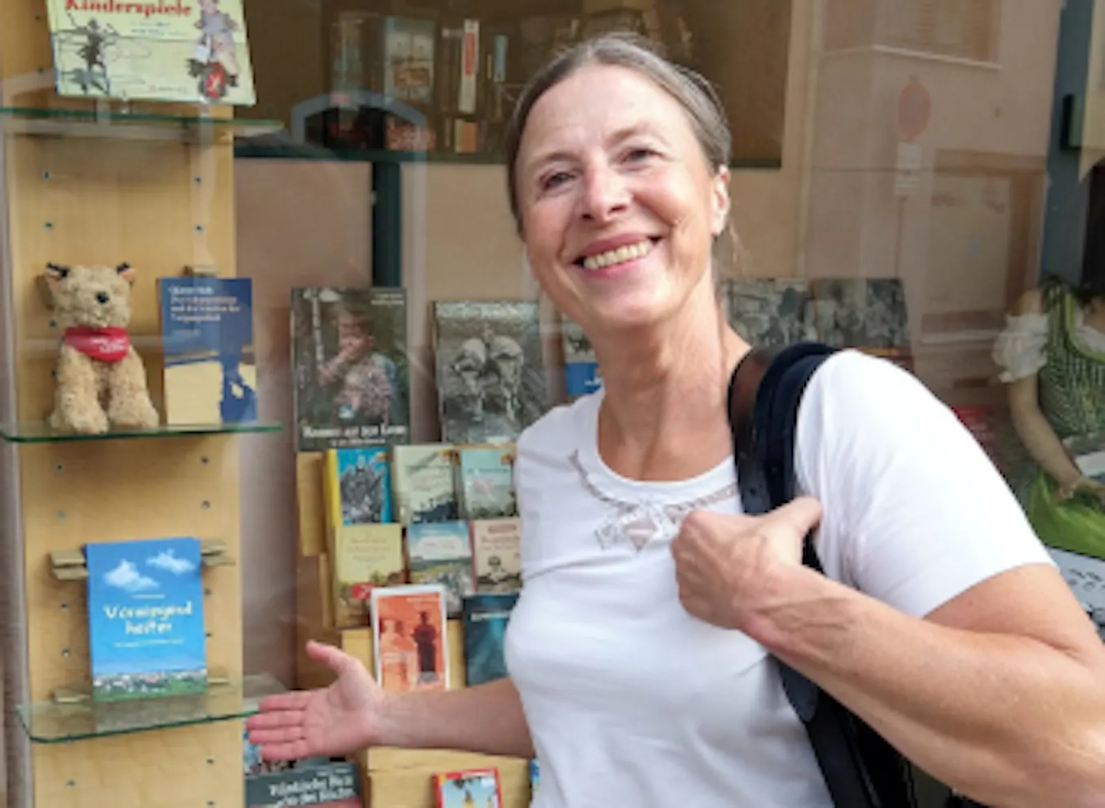 Steffi Zachmeier weist auf das neue Buch "Vorwiegend heiter" in einem Schaufenster mit noch anderen Büchern