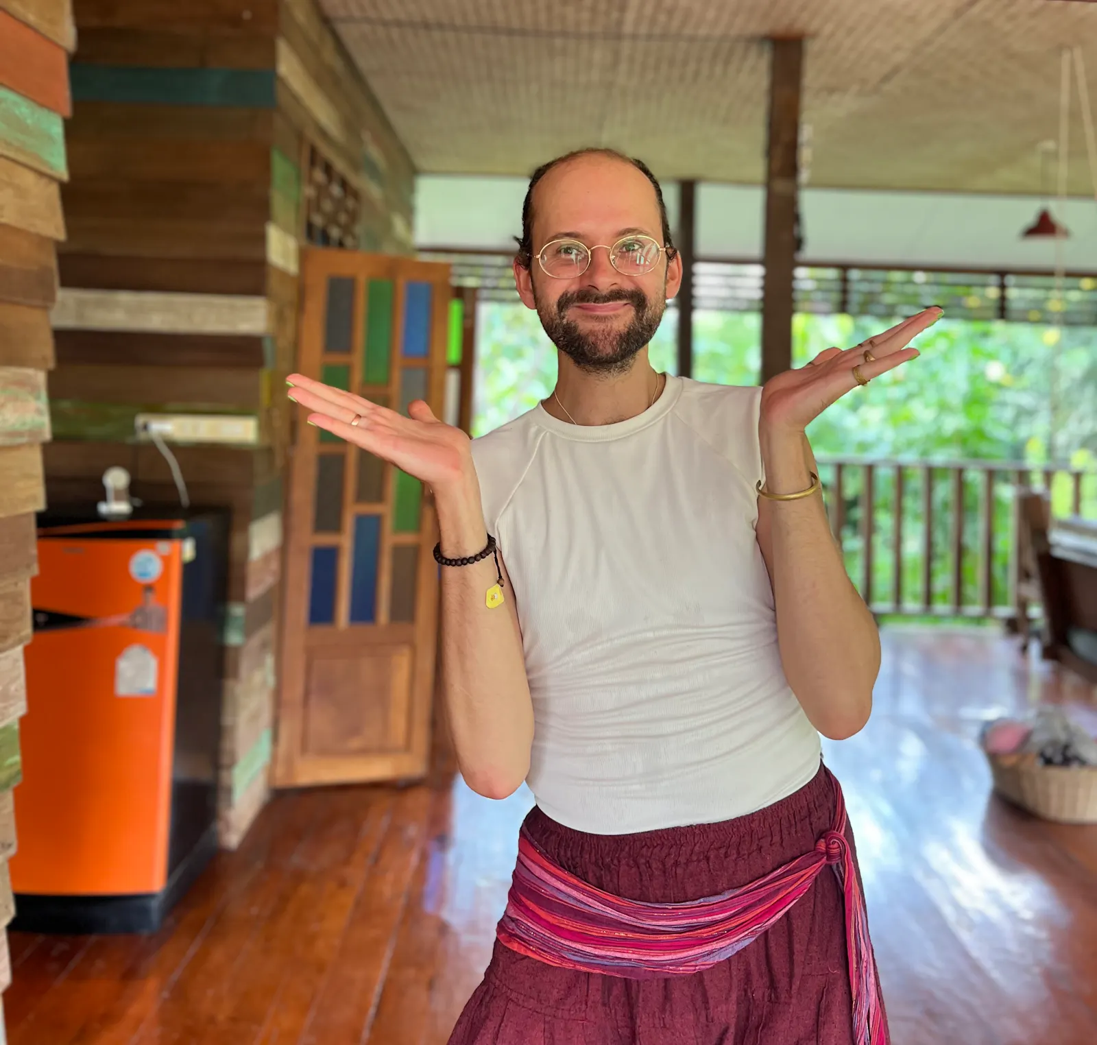 Olaf steht auf einer Terrasse in einem weißen T-Shirt und roter Hose und hat die Hände ausgestreckt.