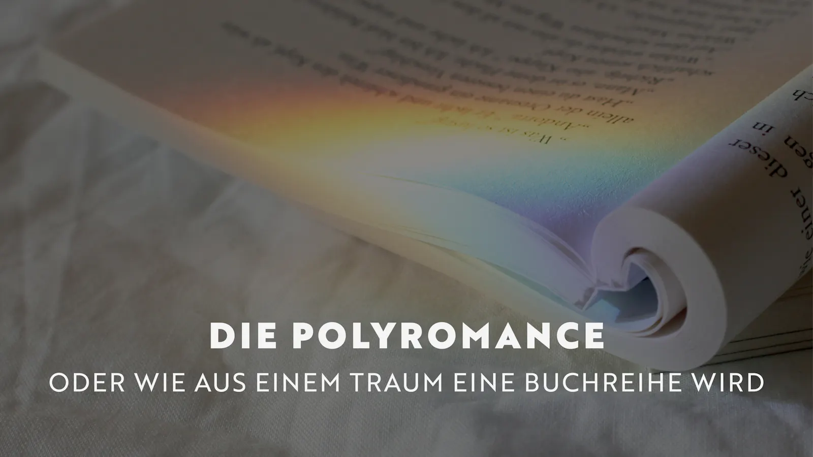 Im Hintergrund ein aufgeschlagenes Buch auf dessen Seiten eine Regenbogenreflexion zu sehen ist. Im Vordergrund der Titel: Die Polyromance- oder wie aus einem Traum eine Buchreihe wird.