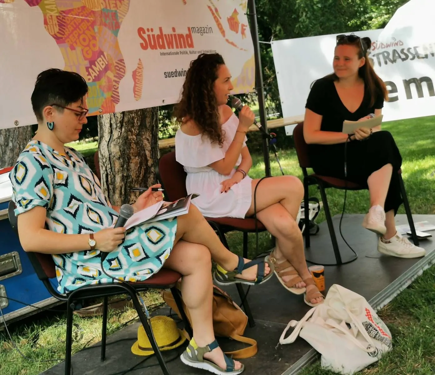 Marcela Torres Heredia, Sarah Espinosa und Milena sitzen auf einem Podium. Sarah spricht gerade ins Mikrofon.